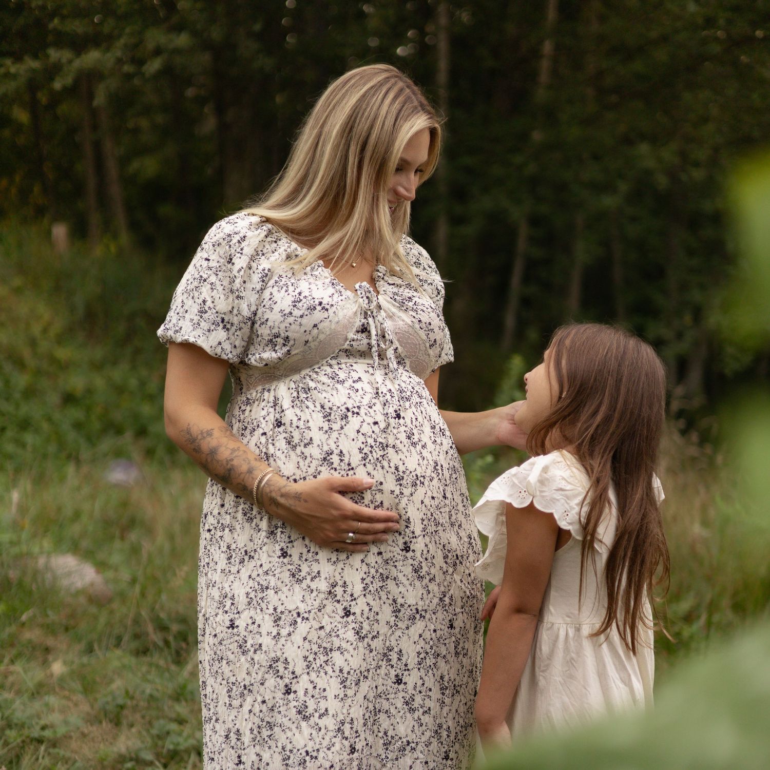 Maternity photography session in British Columbia capturing a mother and daughter sharing a tender moment outdoors.