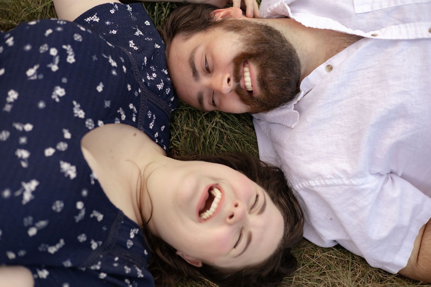 People lying on grass in a circle formation wearing navy and white clothing, viewed from above.