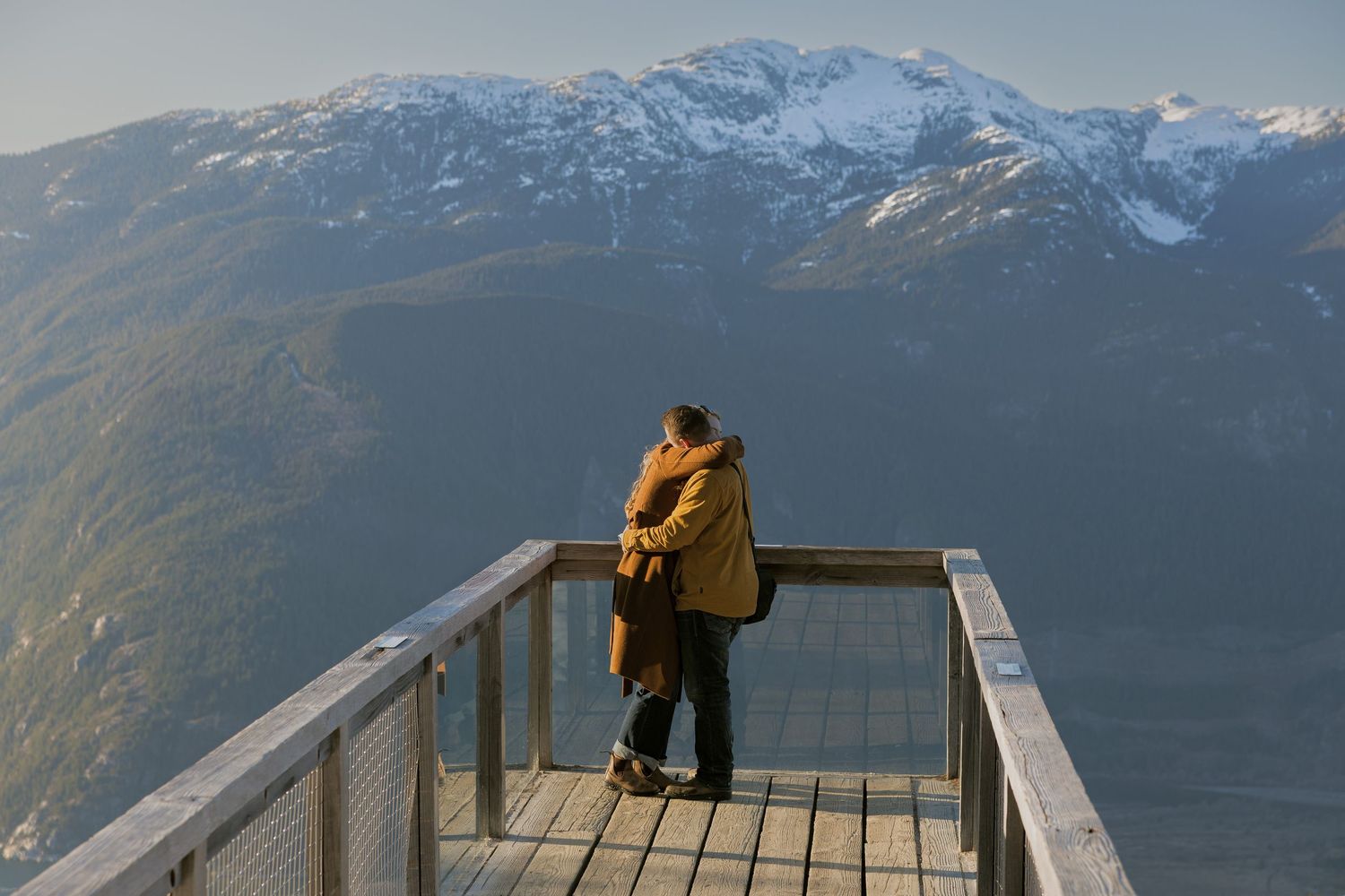 Candid proposal photography capturing a newly engaged couple celebrating after a surprise mountain proposal.