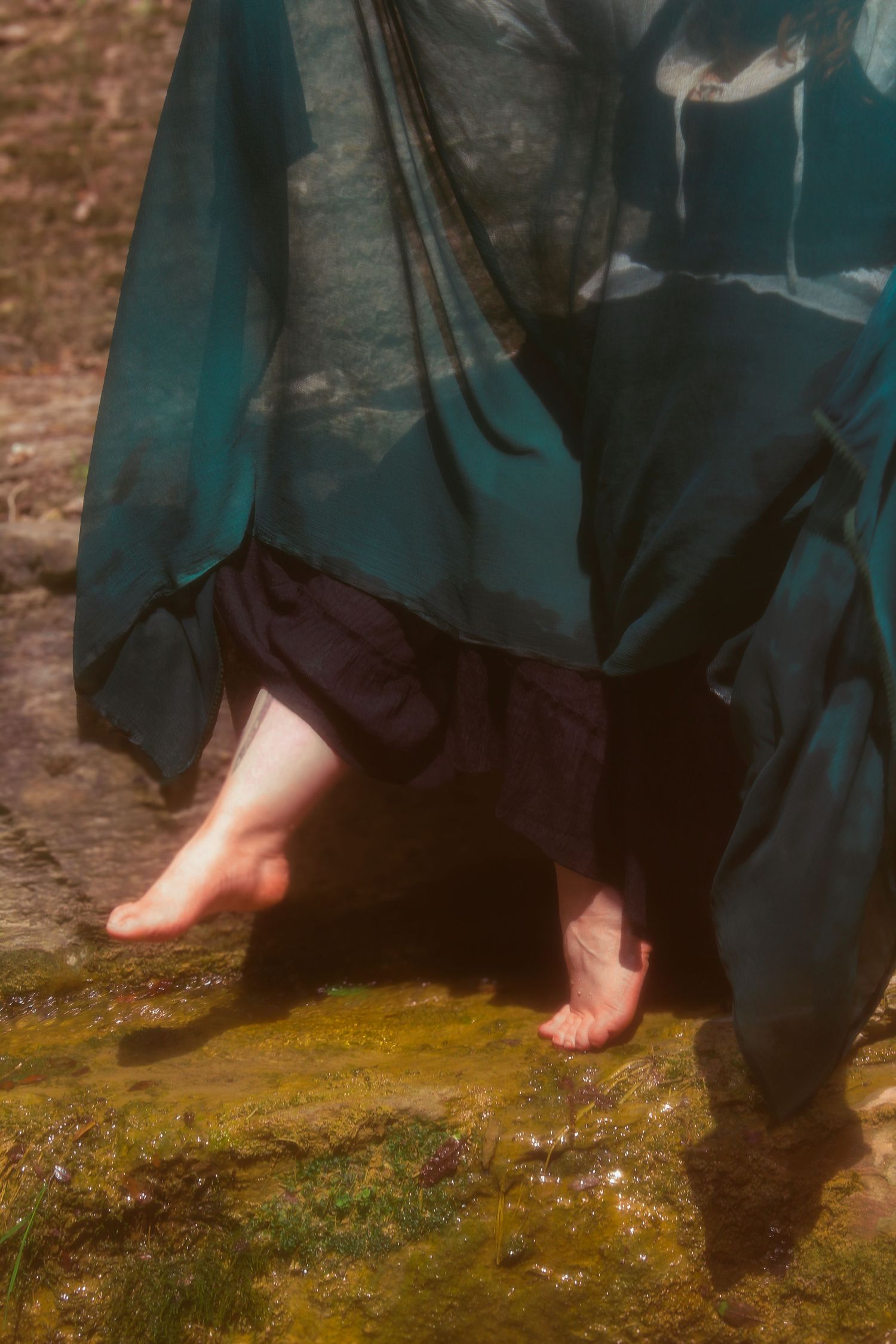 Image de shooting pied avec une lumière tamisée et une ambiance rêveuse. Portrait artistique en extérieur, mettant en scène un univers fée