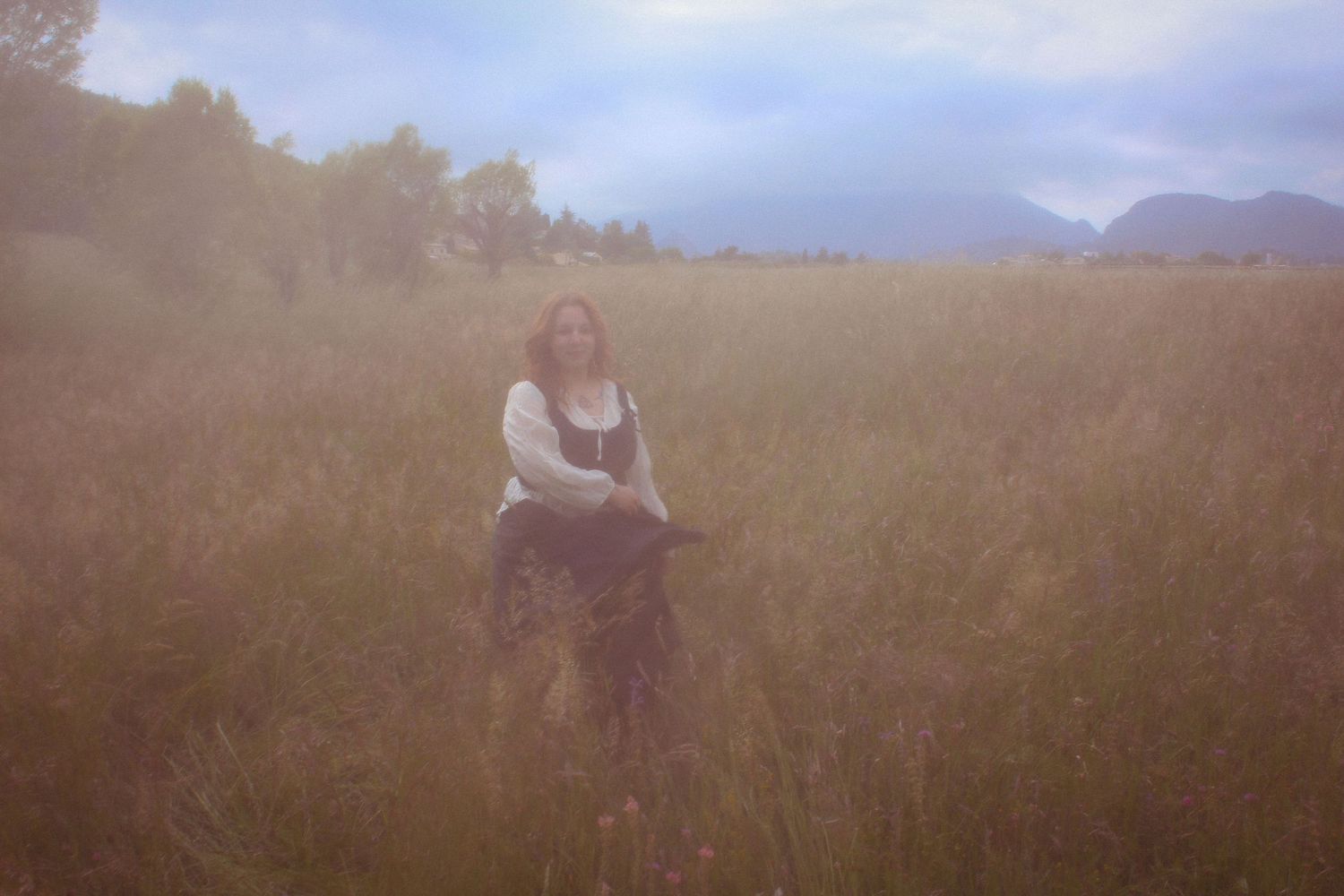 Image de shooting Mystic avec une lumière tamisée et une ambiance rêveuse. Portrait artistique en extérieur, mettant en scène un univers fée