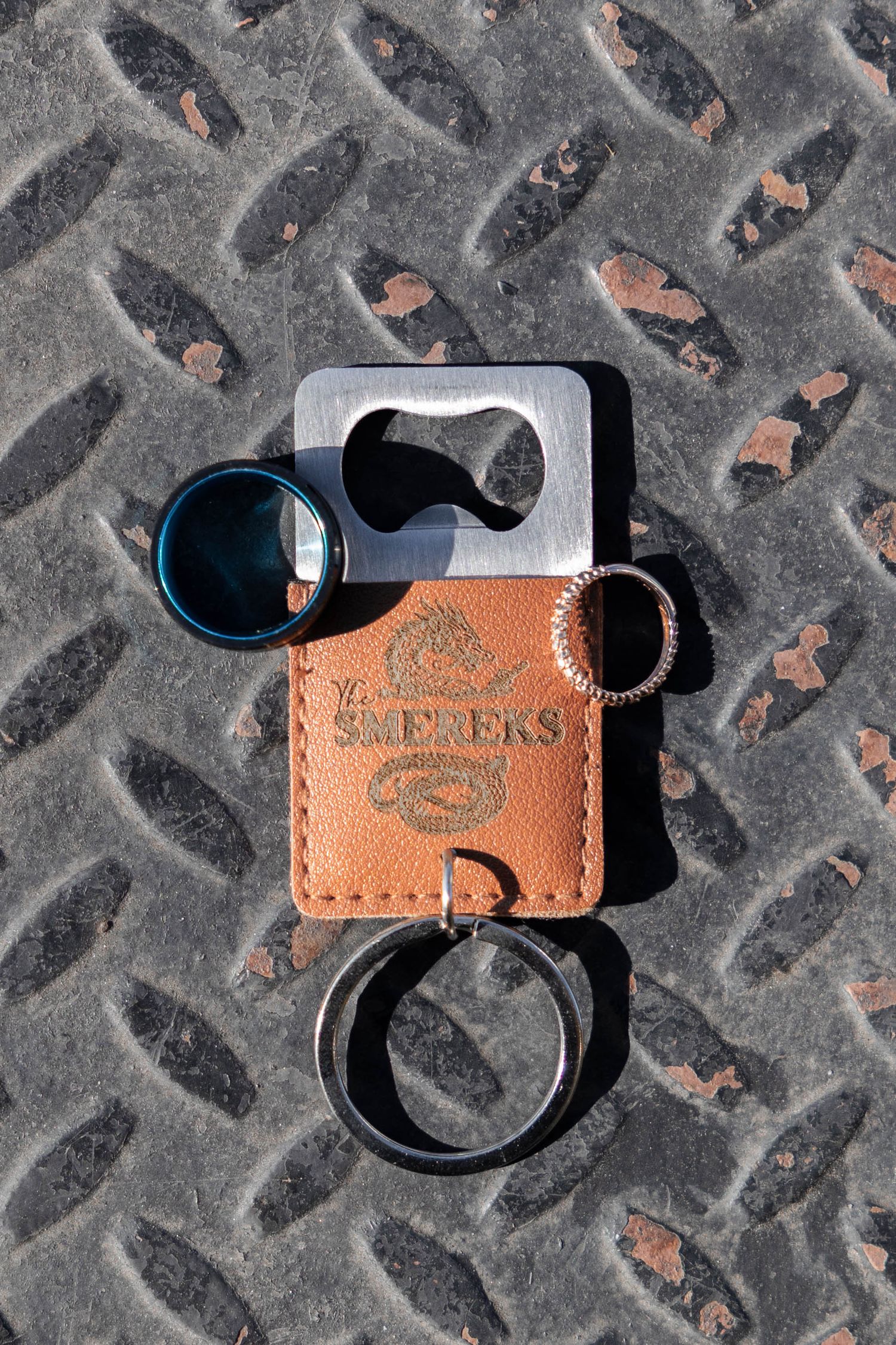 Leather AirPods case and carabiner clip shown against textured metal diamond plate surface.