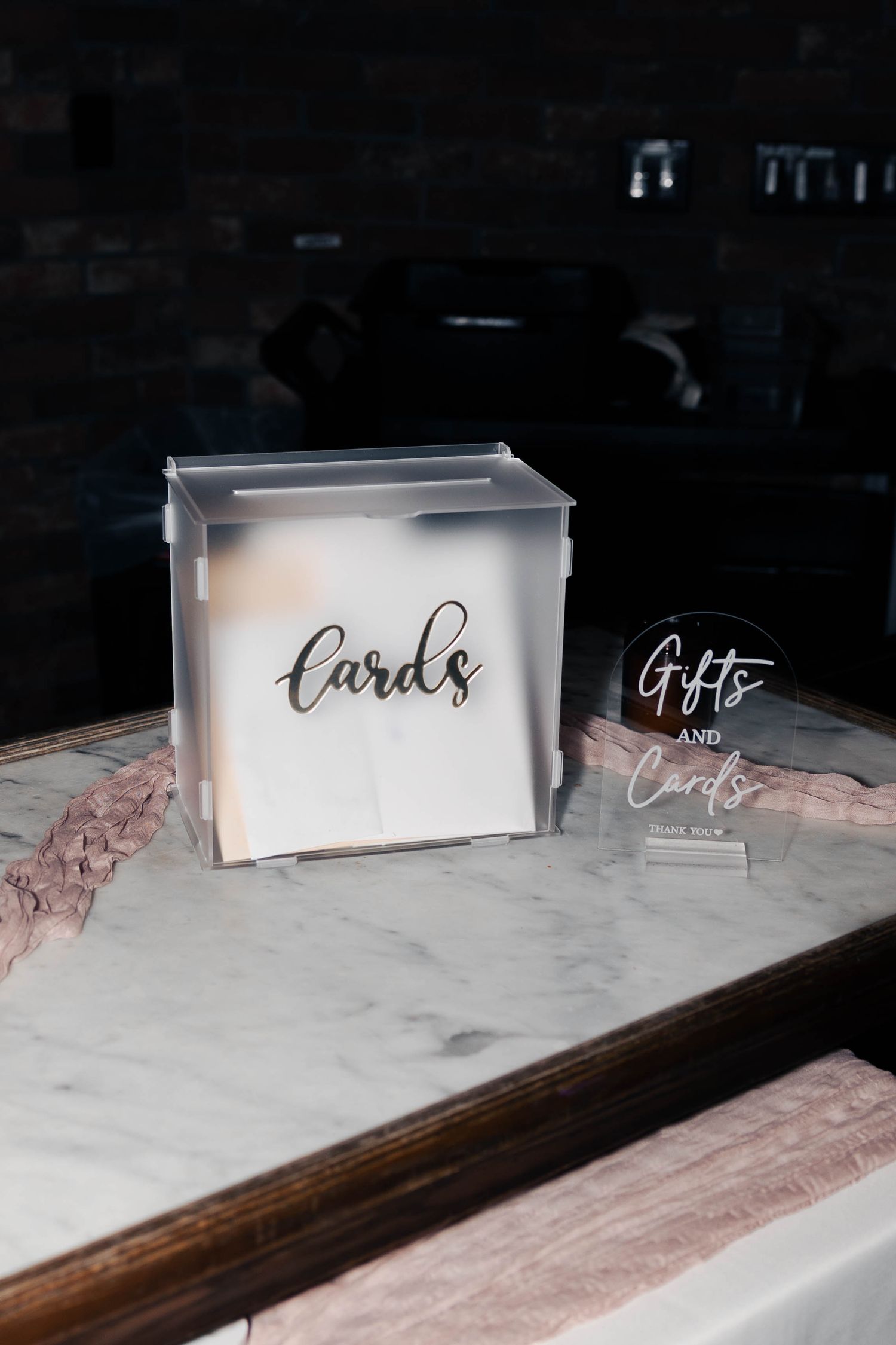 Wedding place cards and signage displayed on a marble surface with elegant calligraphy in monochromatic tones.
