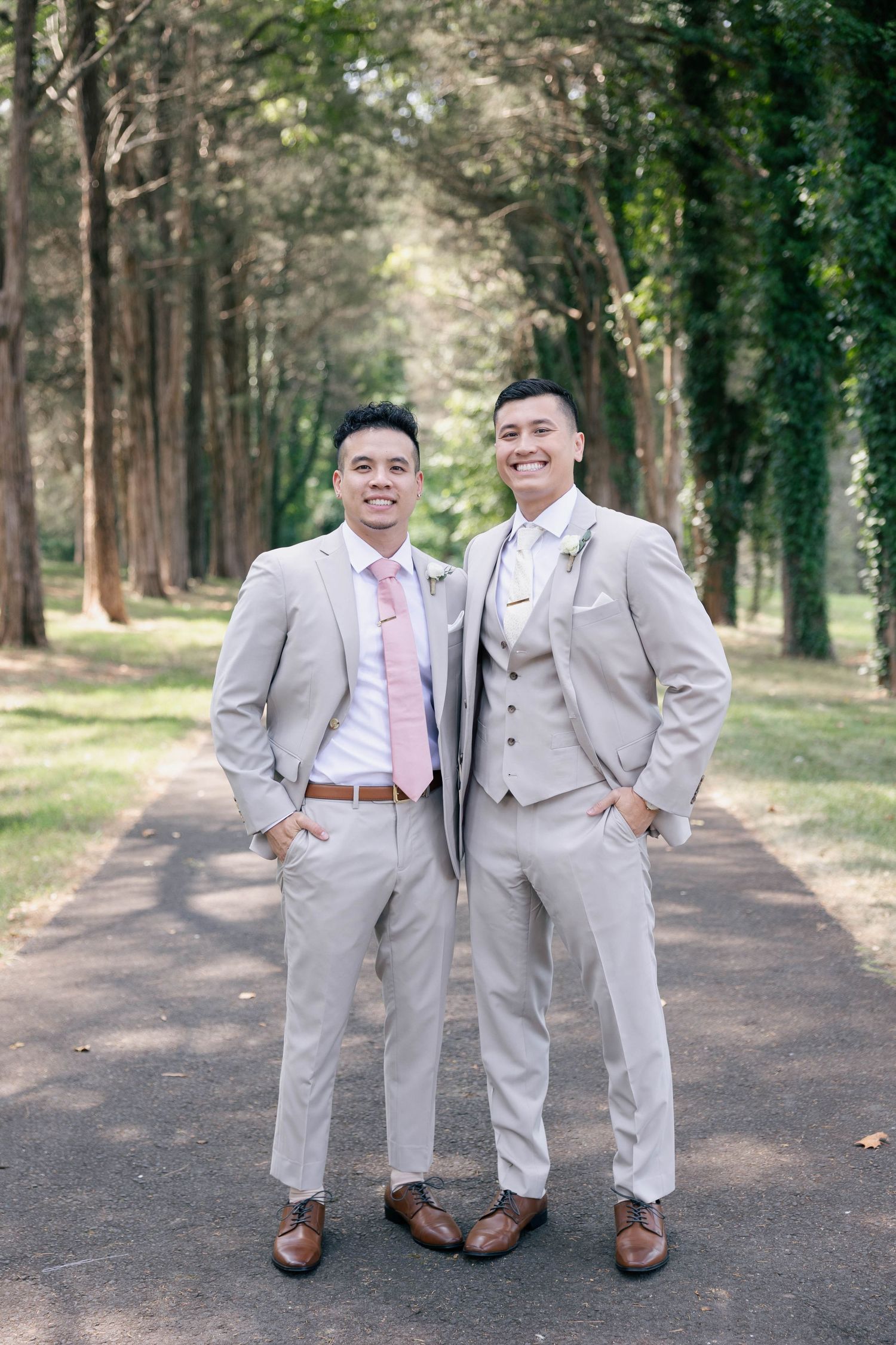 Groomsmen sharing laughs while posing in light gray suits on forest path.Groom and groomsmen wedding outfit inspiration in tan suit.