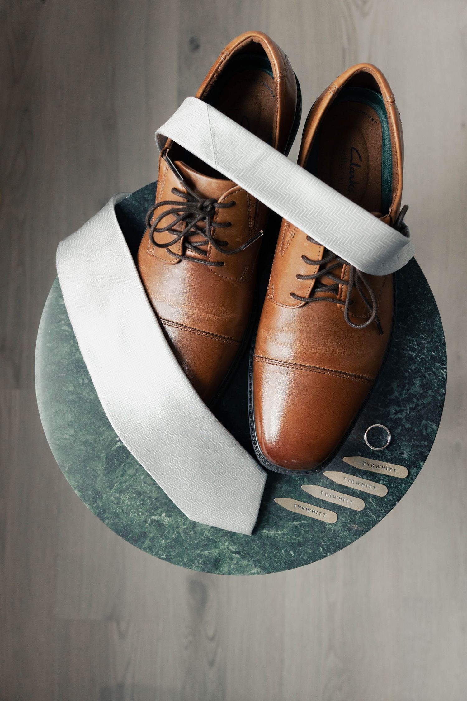 Brown leather oxford dress shoes with white tissue paper displayed on a dark green marble surface from different angles.