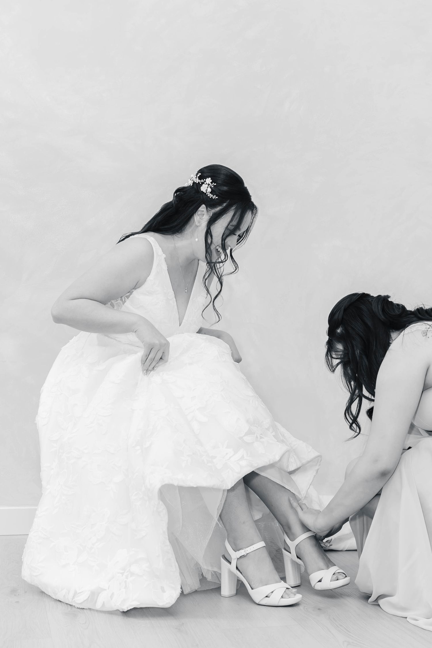 A series of artistic black and white photos showing a person in a white dress crouching and posing on the floor.