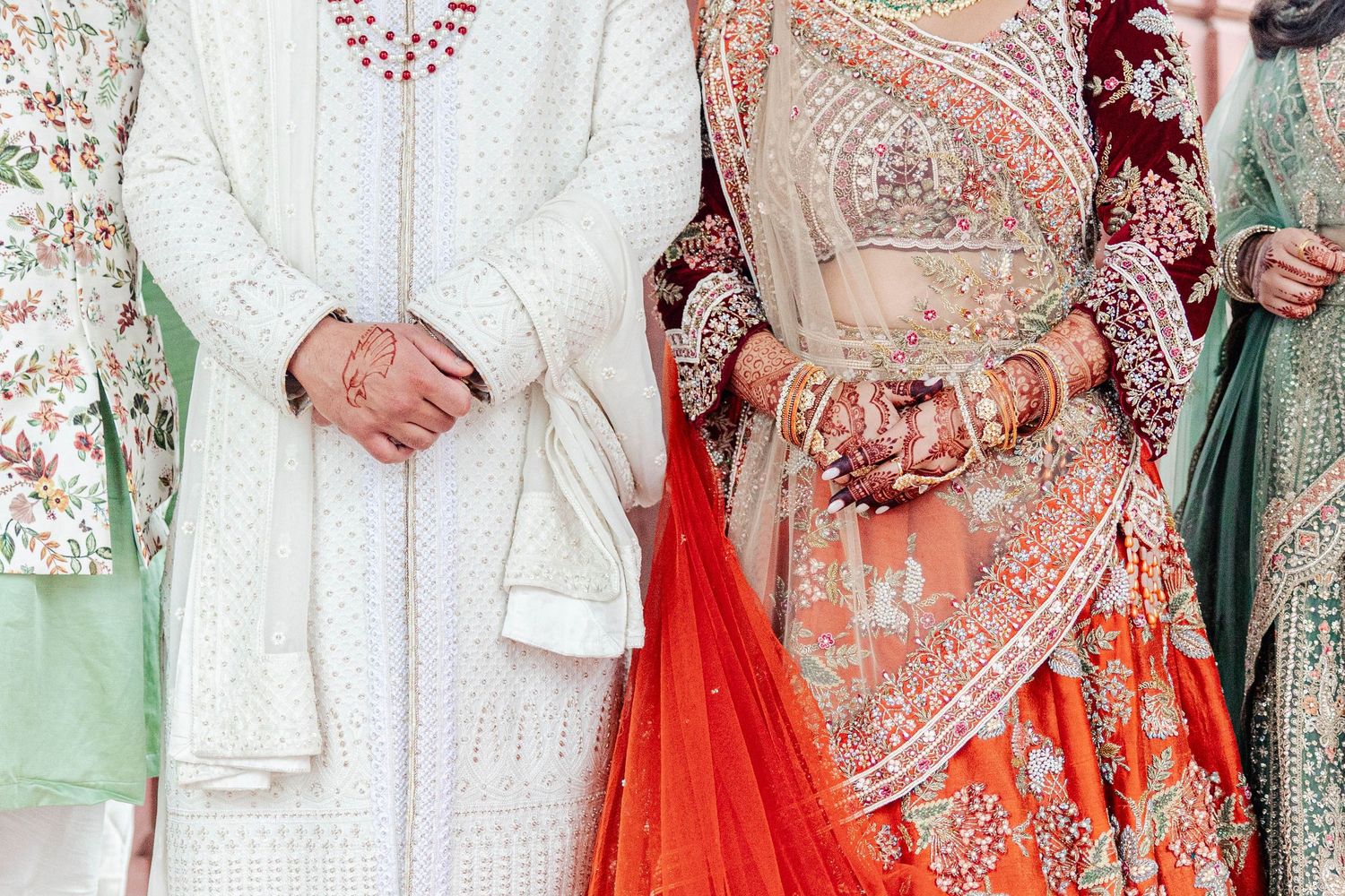 Traditional Indian wedding attire featuring intricate embroidery and bright red lehenga with gold details.
