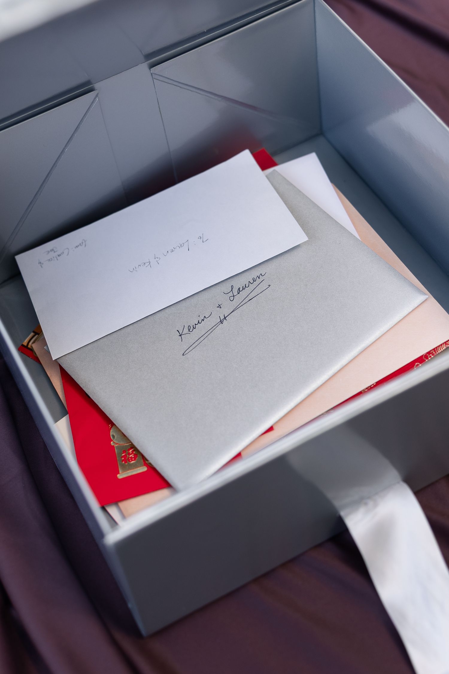 Gray gift box with handwritten cards and envelopes, including a note reading Kevin and Lauren, with red accents.