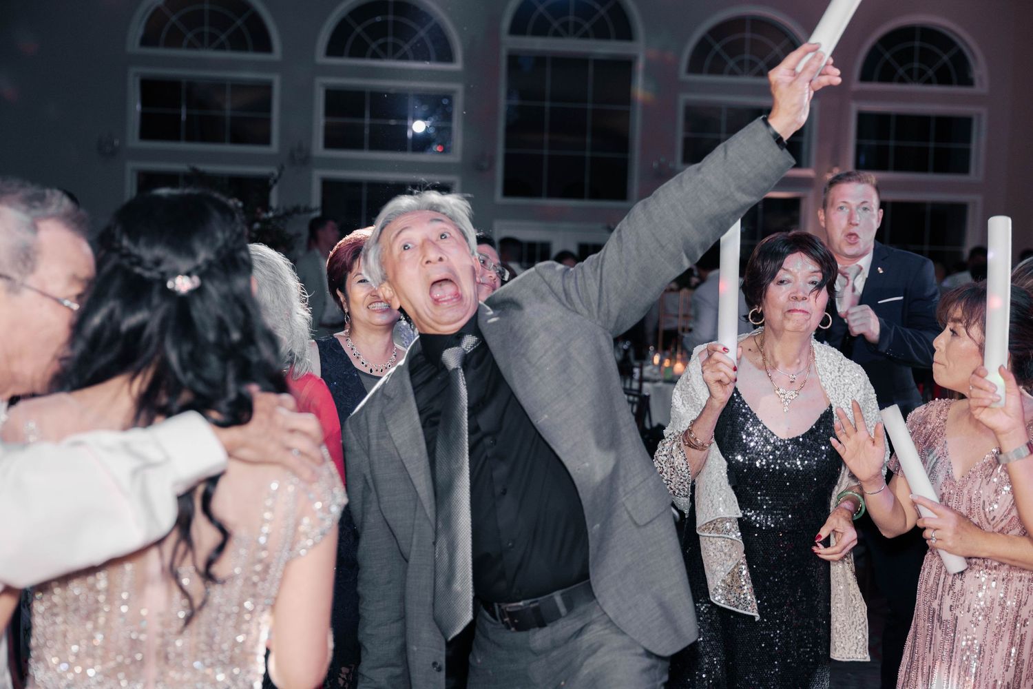 Wedding reception guests dancing and celebrating on the dance floor.