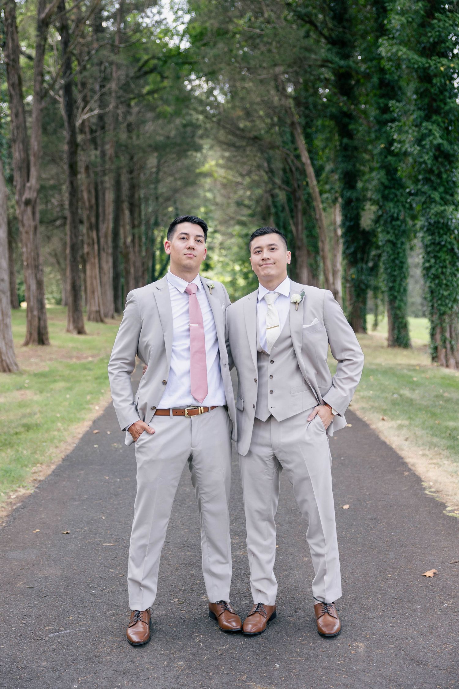 Groomsmen in coordinated gray suits and brown shoes stand together on forest path.Groom and groomsmen wedding outfit inspiration in tan suit