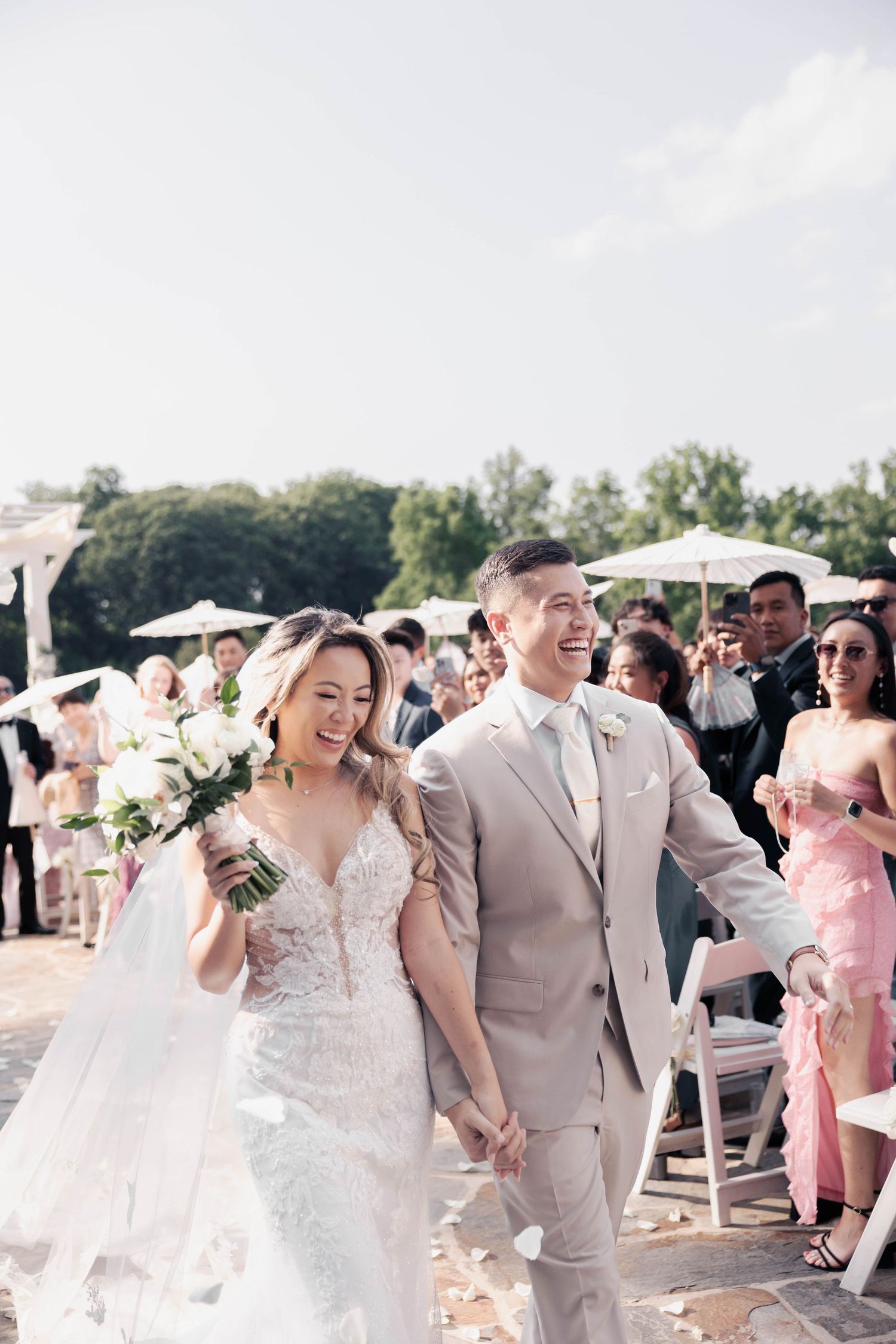 Wedding guests and bridal party celebrate during outdoor ceremony under bright sunlight.