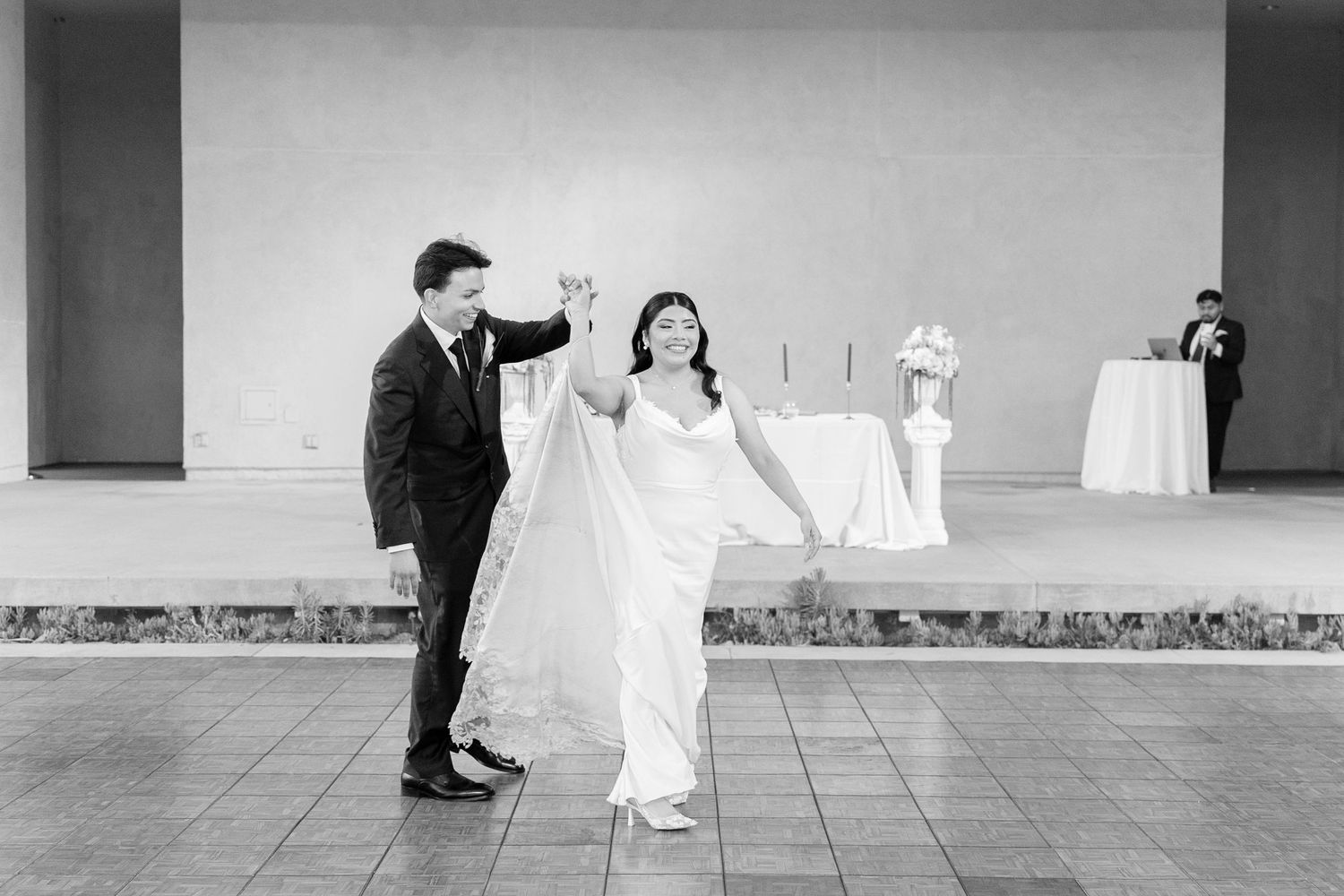 Black and white photo of a bride and groom sharing their first dance at an elegant wedding reception.