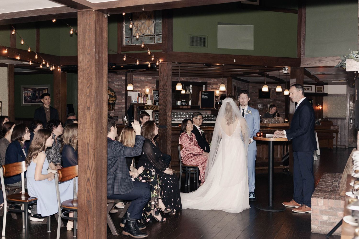 Reception venue with exposed wooden beams and brick walls filled with wedding guests.