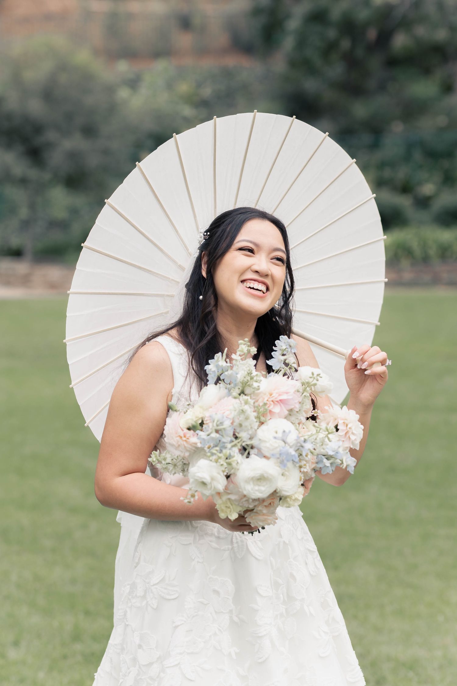 Wedding photography with white parasol and floral bouquet in an outdoor setting.