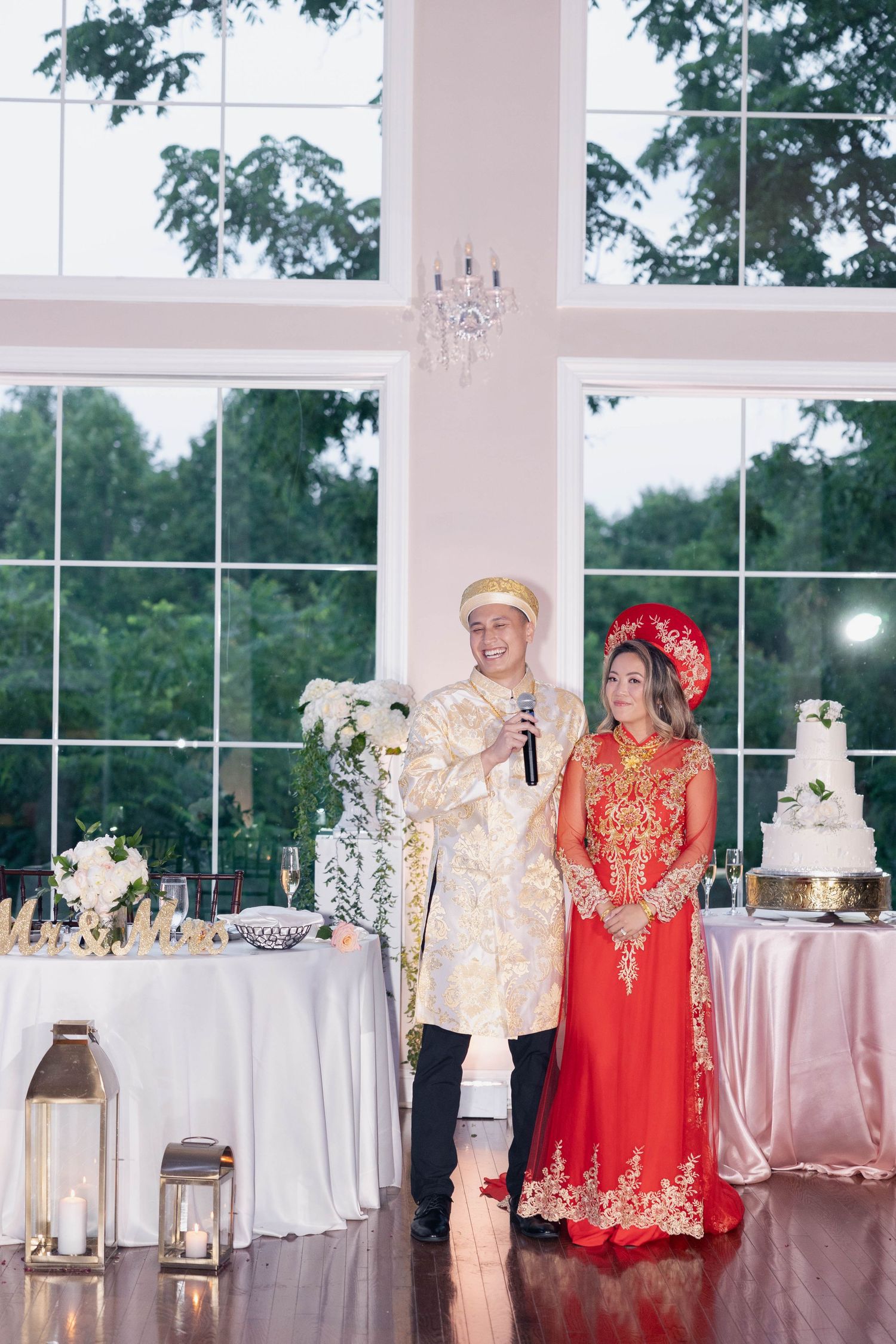 Traditional Vietnamese wedding attire in red and gold displayed alongside white tables in an elegant reception venue.