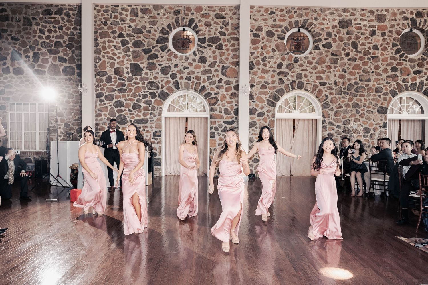 Celebration sequence showing dance moves in an elegant stone venue with arched windows.