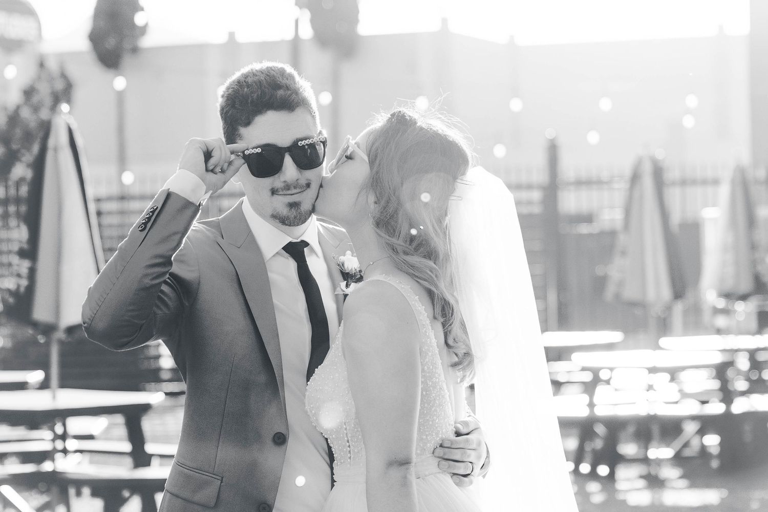 A vintage black and white photo shows an elegant couple embracing at an outdoor venue.
