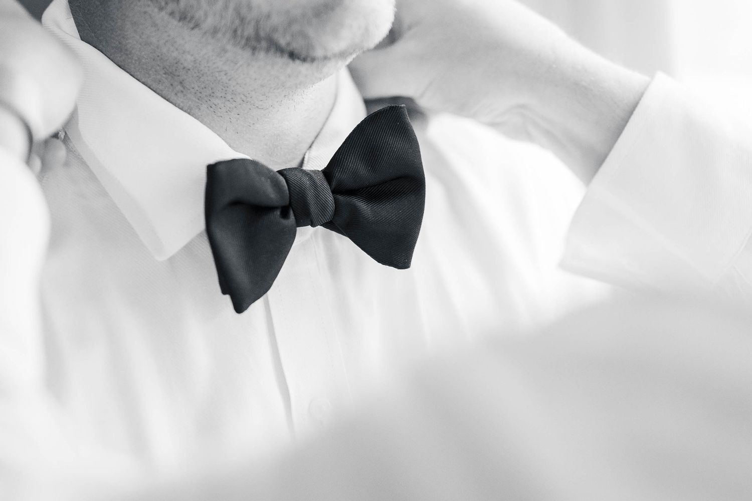 Black and white close-up details of formal attire with bow tie and suit.