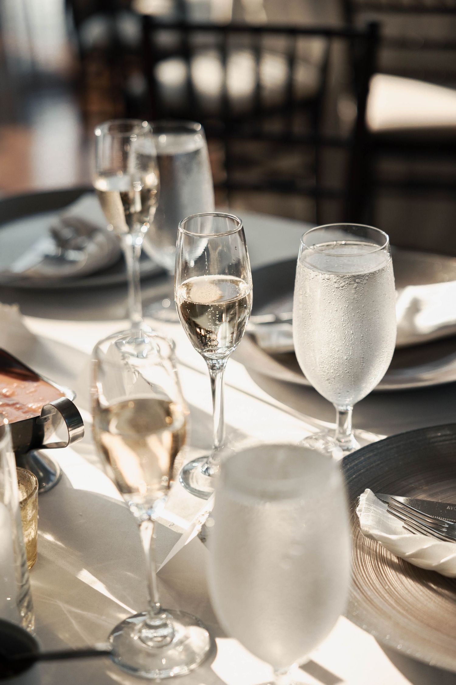 Elegant table setting with wine glasses catching sunlight at a formal dining event.