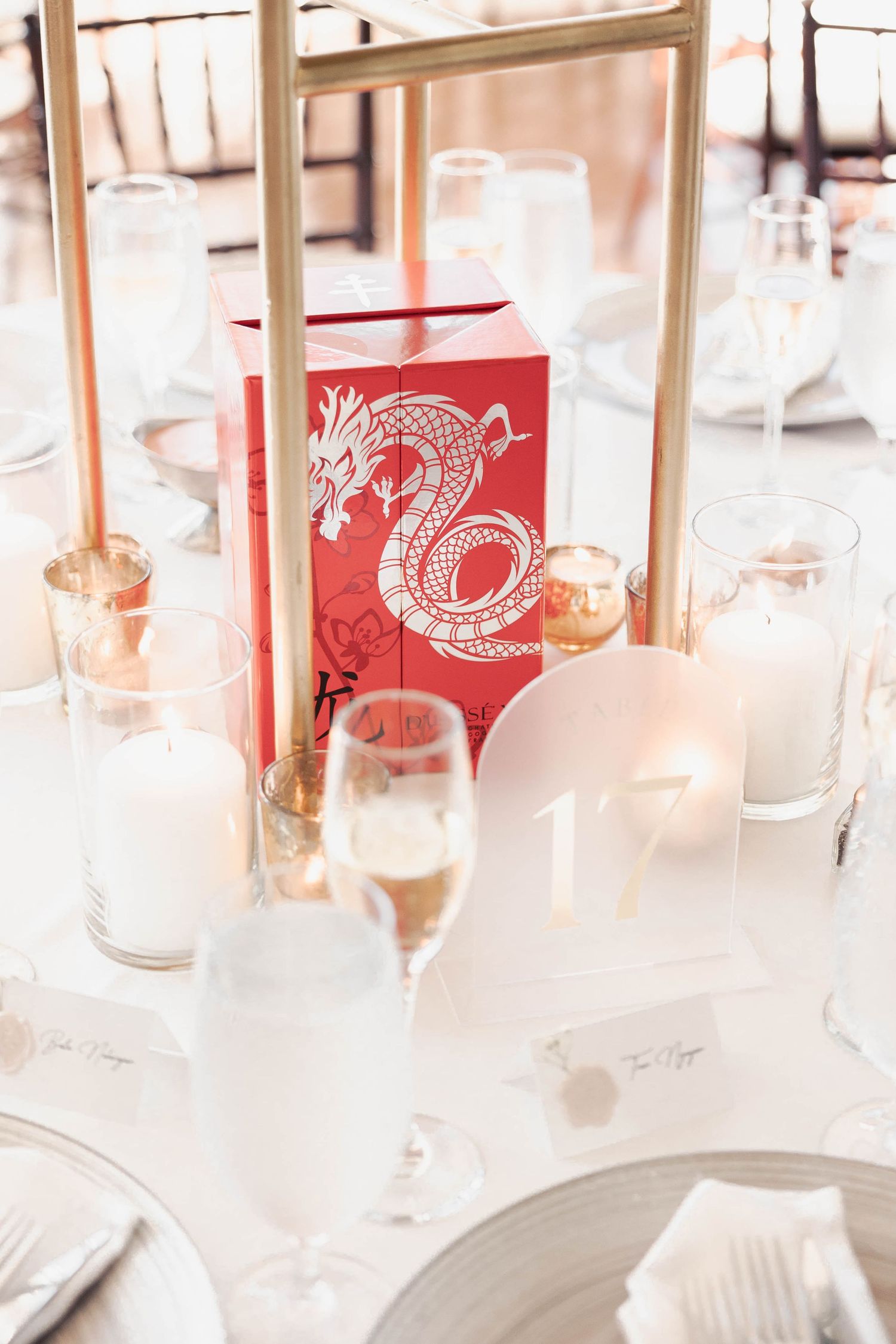 Wedding reception table settings with red place cards and champagne glasses.