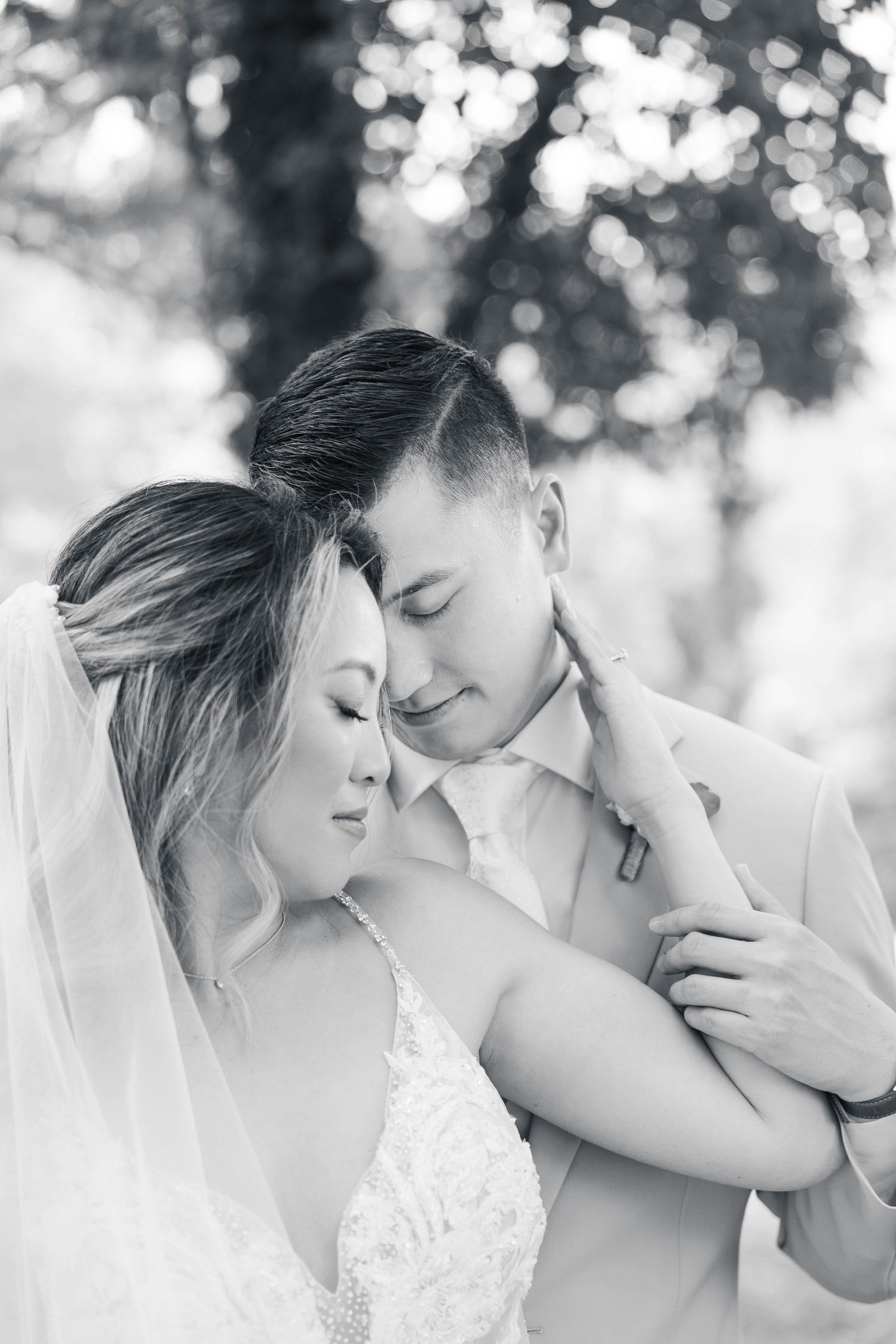 A tender black and white wedding portrait capturing an intimate moment between a bride and groom.