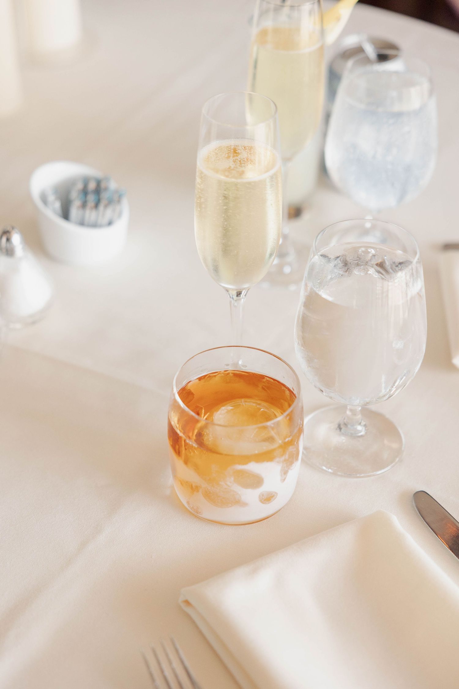 Wedding reception table with champagne glasses and drinks on white tablecloth.