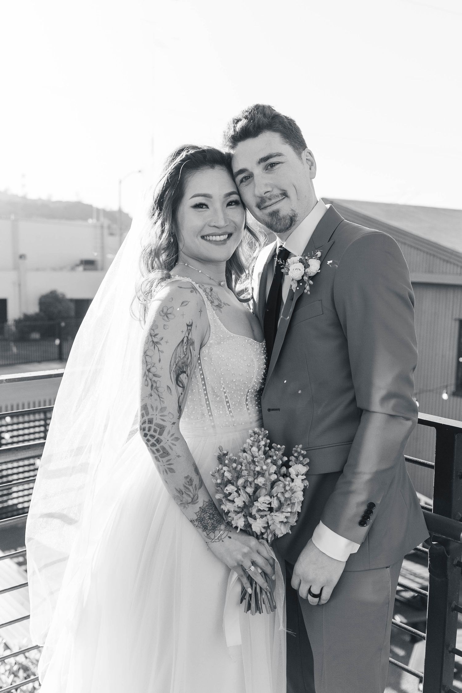Four romantic black and white wedding portraits showing a couple embracing outdoors with a veil and bouquet.