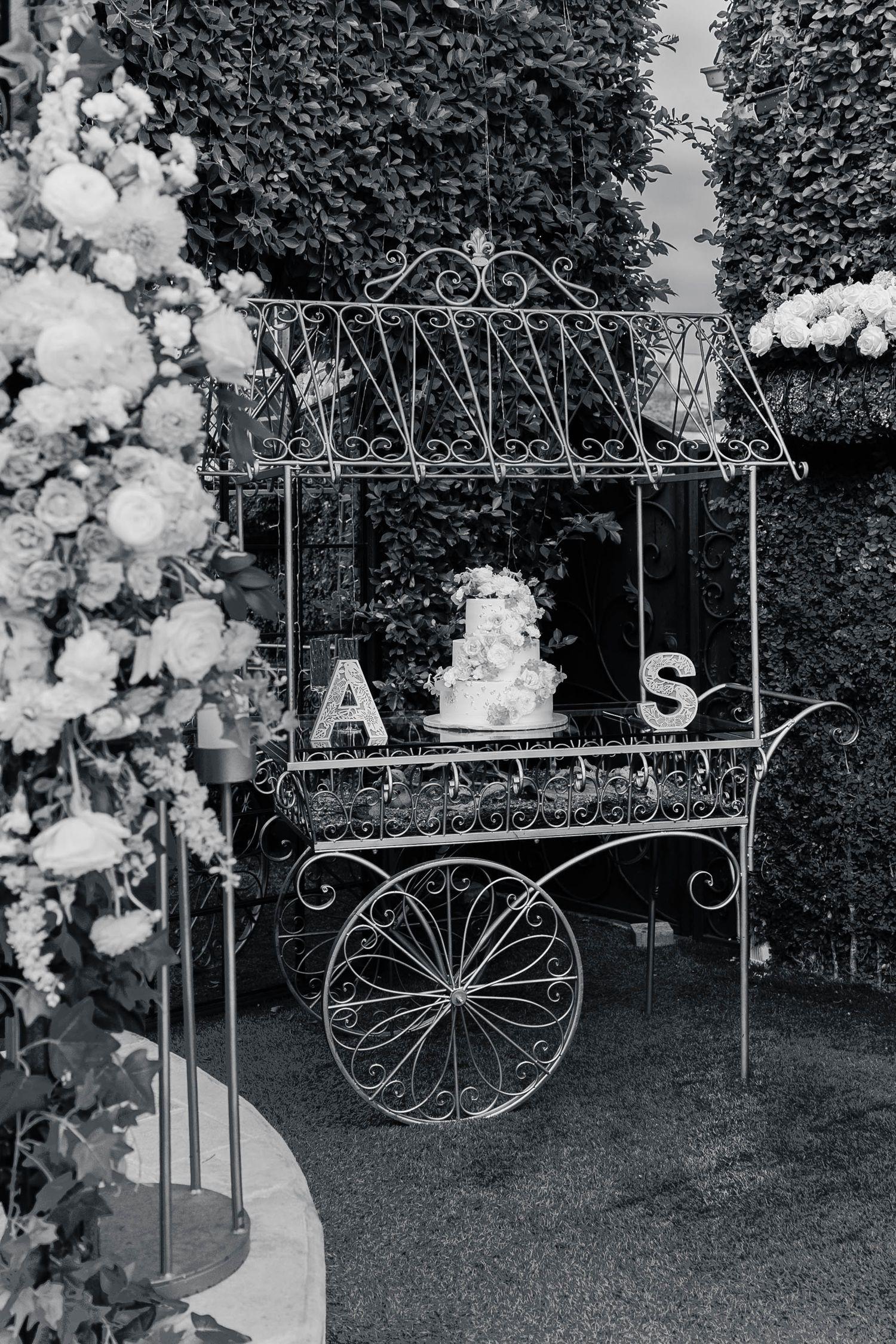 Decorative white metal garden cart adorned with balloon garlands and floral arrangements for an elegant outdoor event setup.