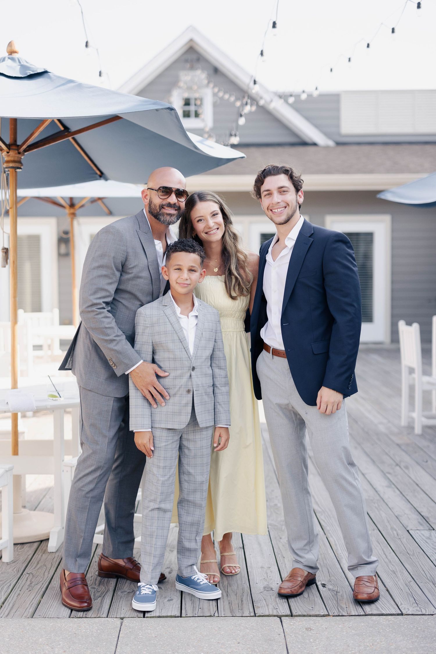 Family group poses on wooden deck wearing coordinated gray and navy formal attire.