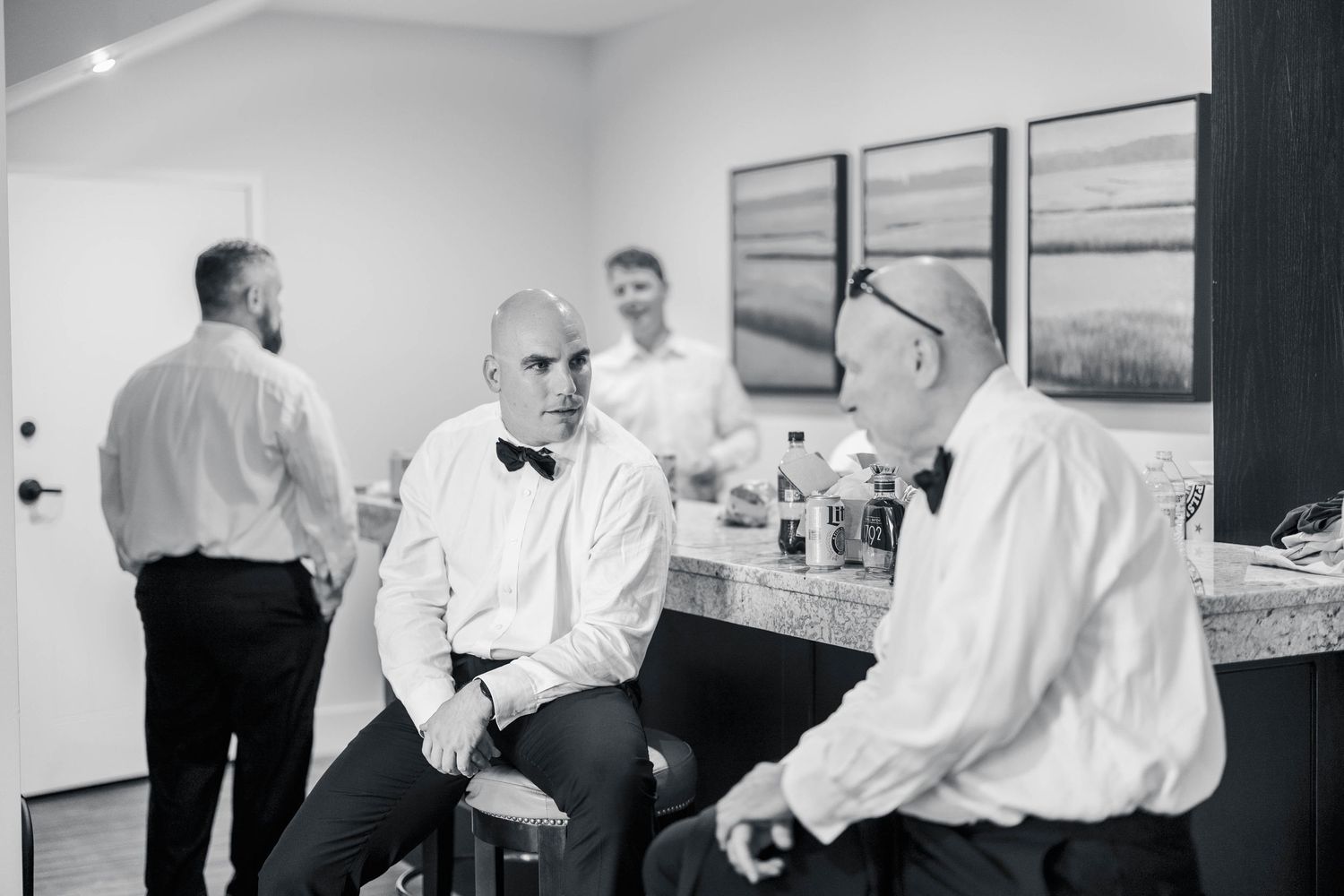 Black and white photos of wedding party members getting ready in a bright indoor space.