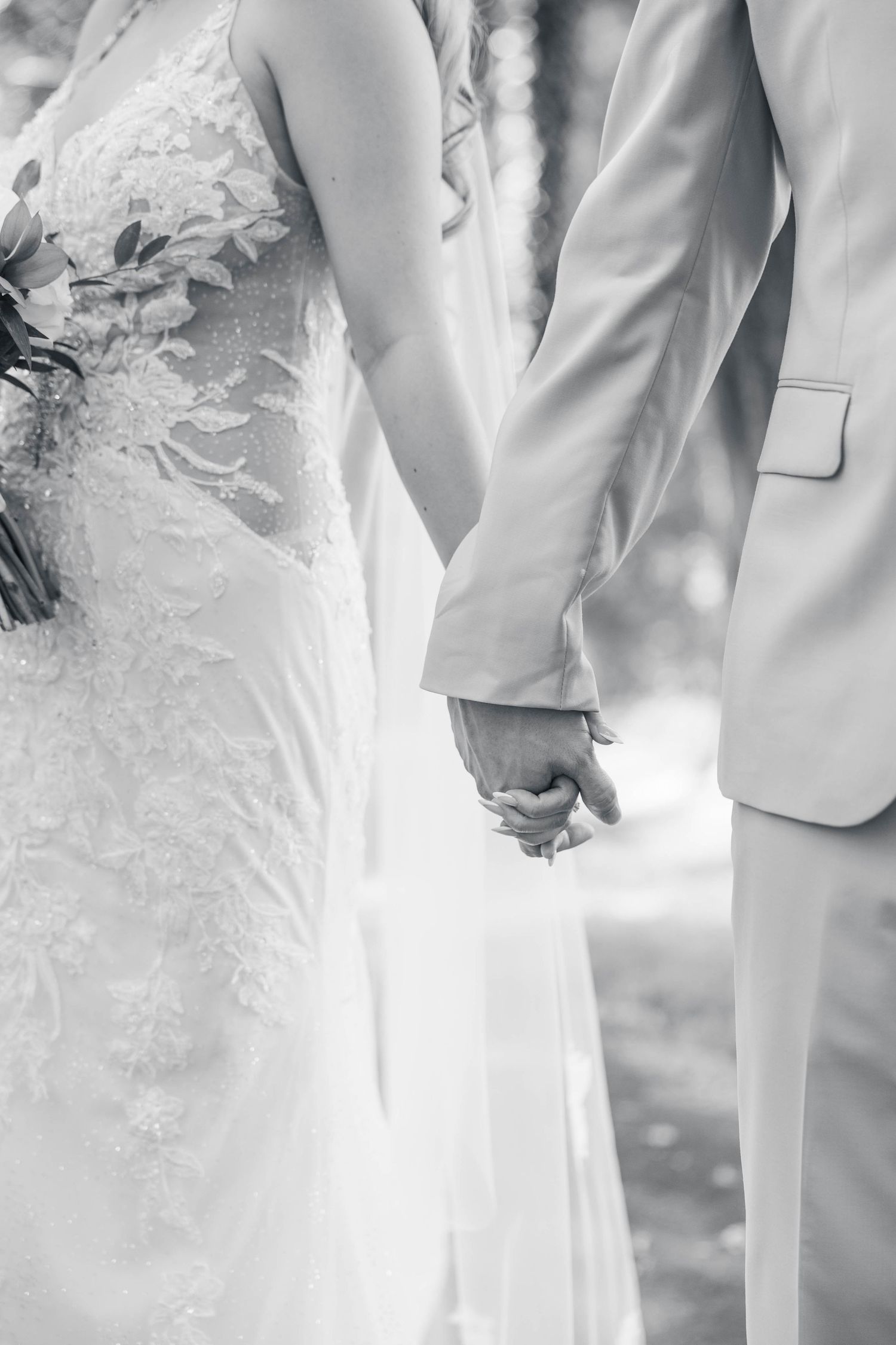 Elegant black and white detail shot of wedding dress lace and suit.