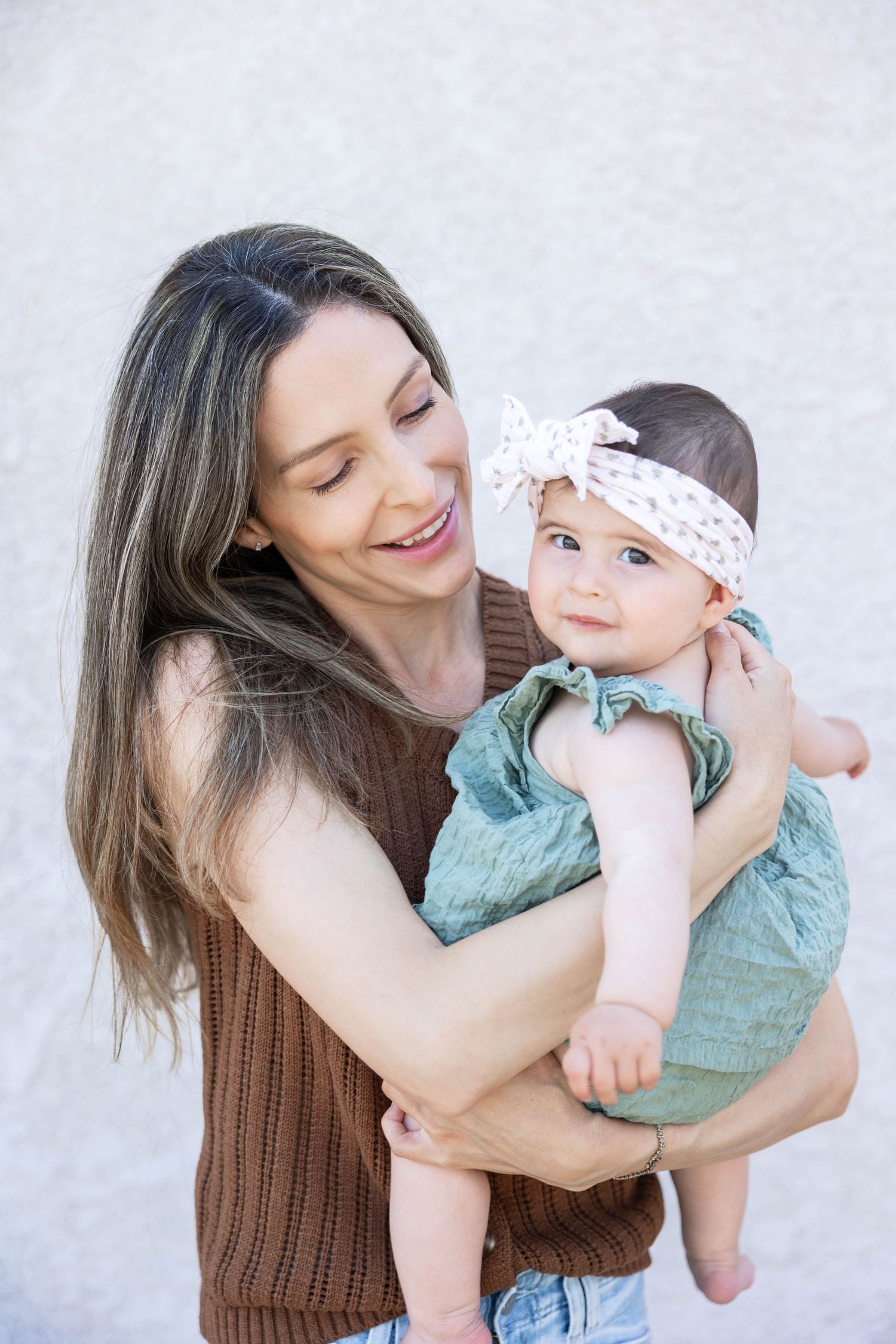 A mother and baby share tender moments together in a series of candid portraits against a light backdrop.