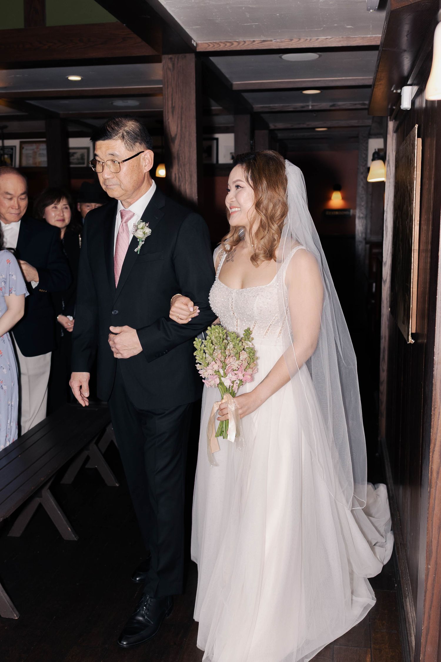 Bride and guests walking through a dimly lit hallway during a wedding ceremony.