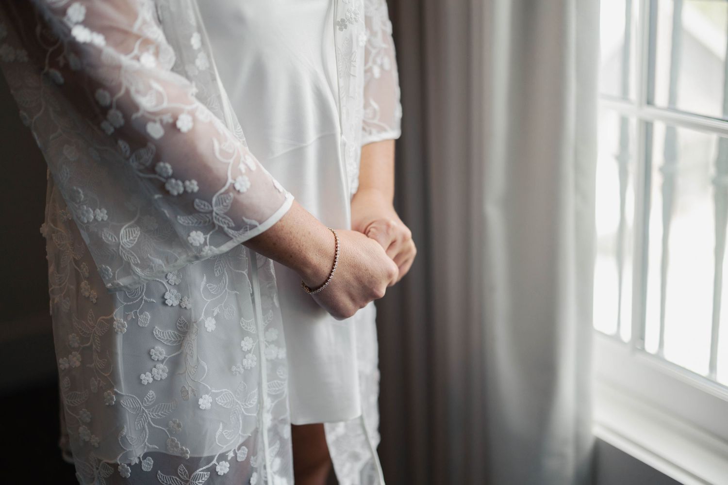 Intimate bridal getting ready moment captured near a bright window.