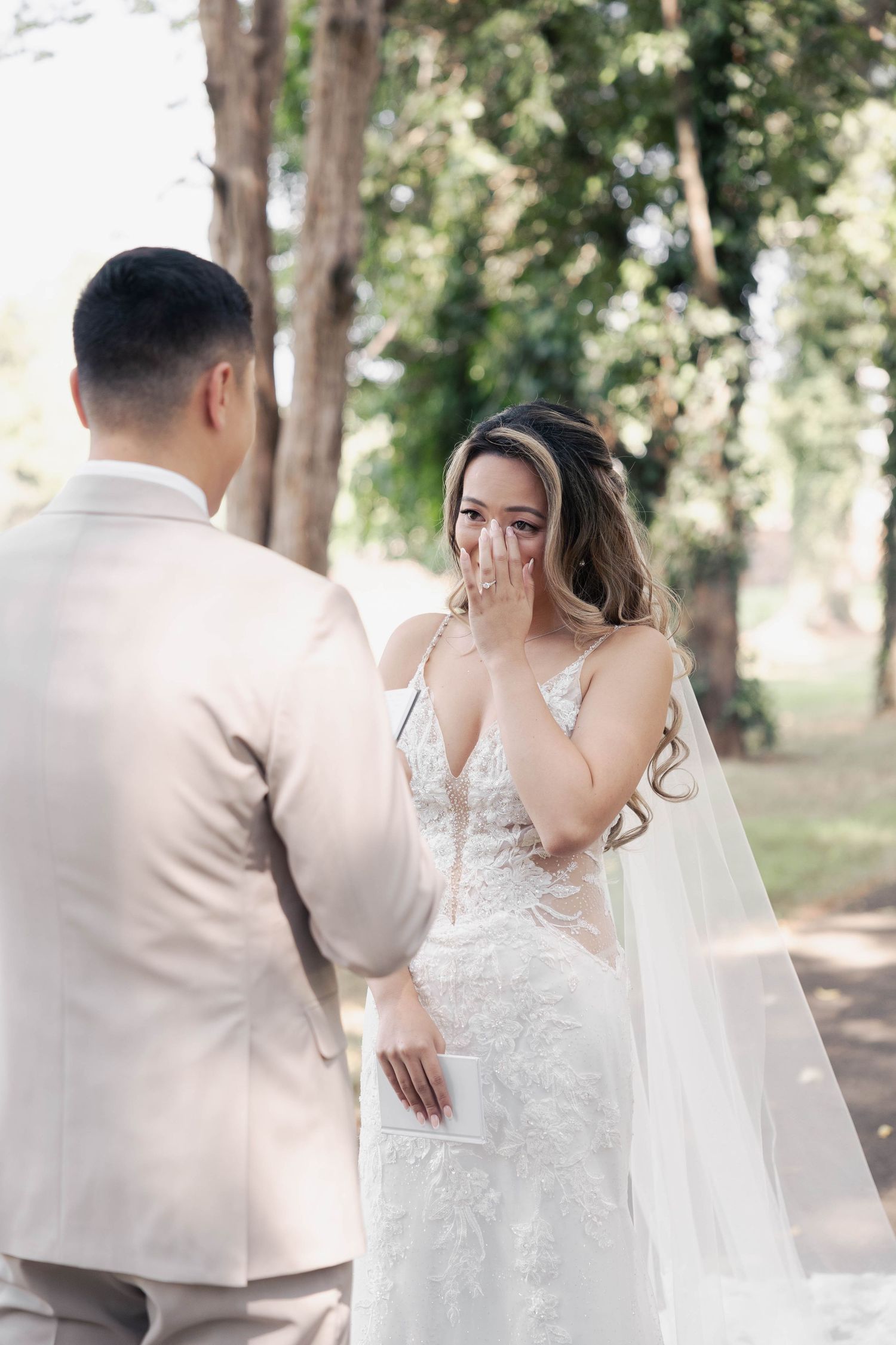 A couple embraces during an emotional first look moment in a wooded setting.