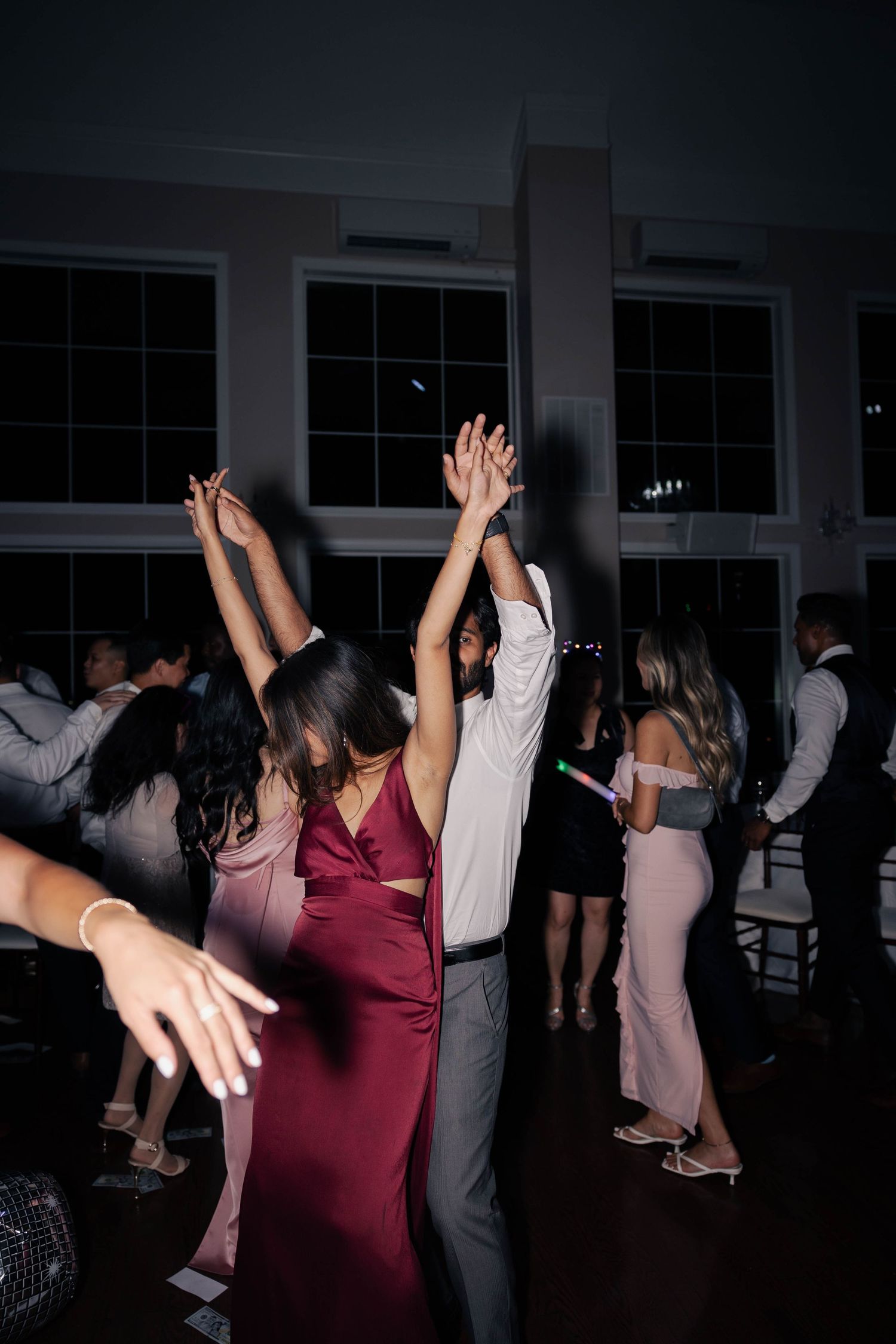 Dance floor filled with guests celebrating at dimly lit wedding reception.
