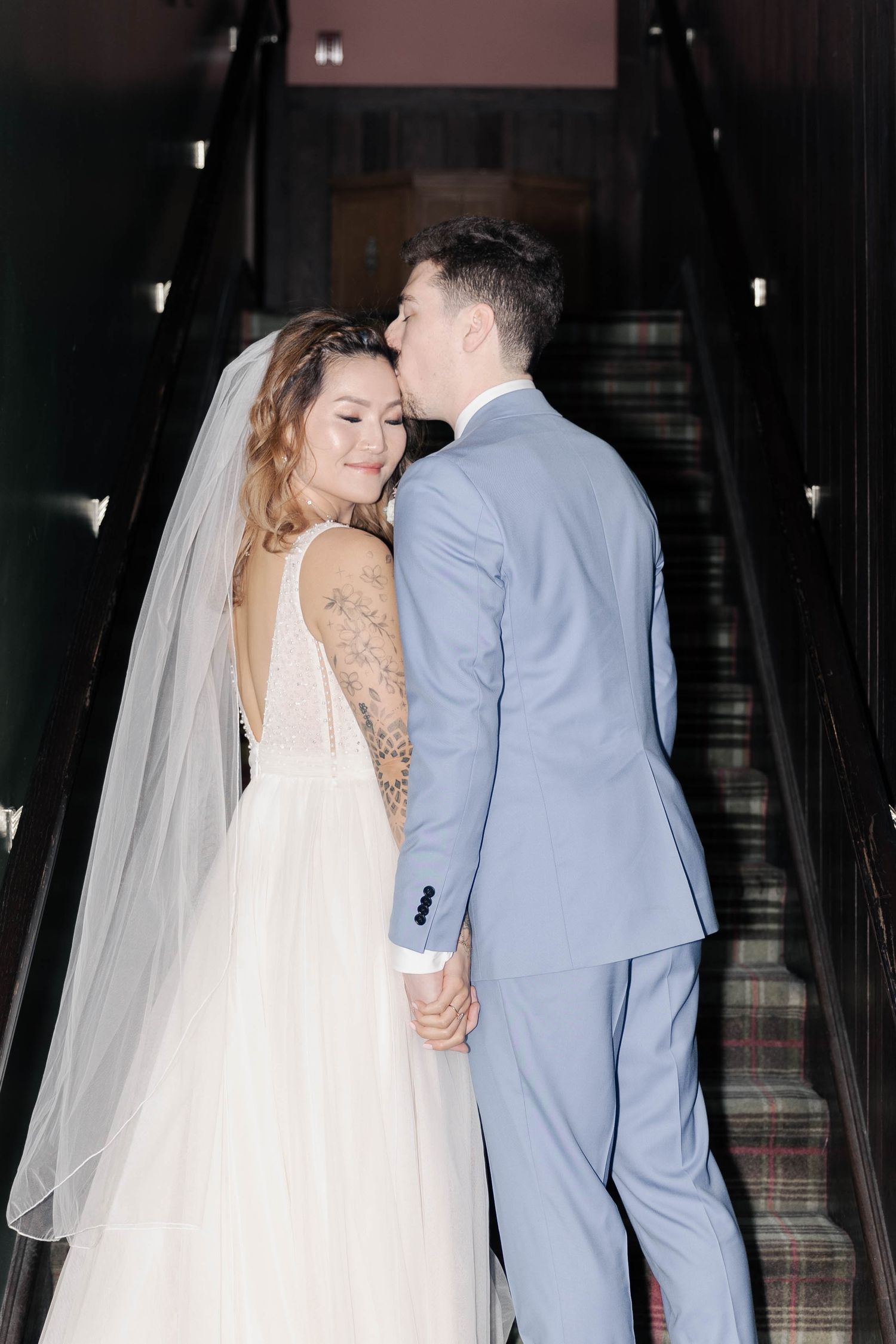 Newlywed couple in white wedding dress and light blue suit share intimate moments during their wedding celebration.