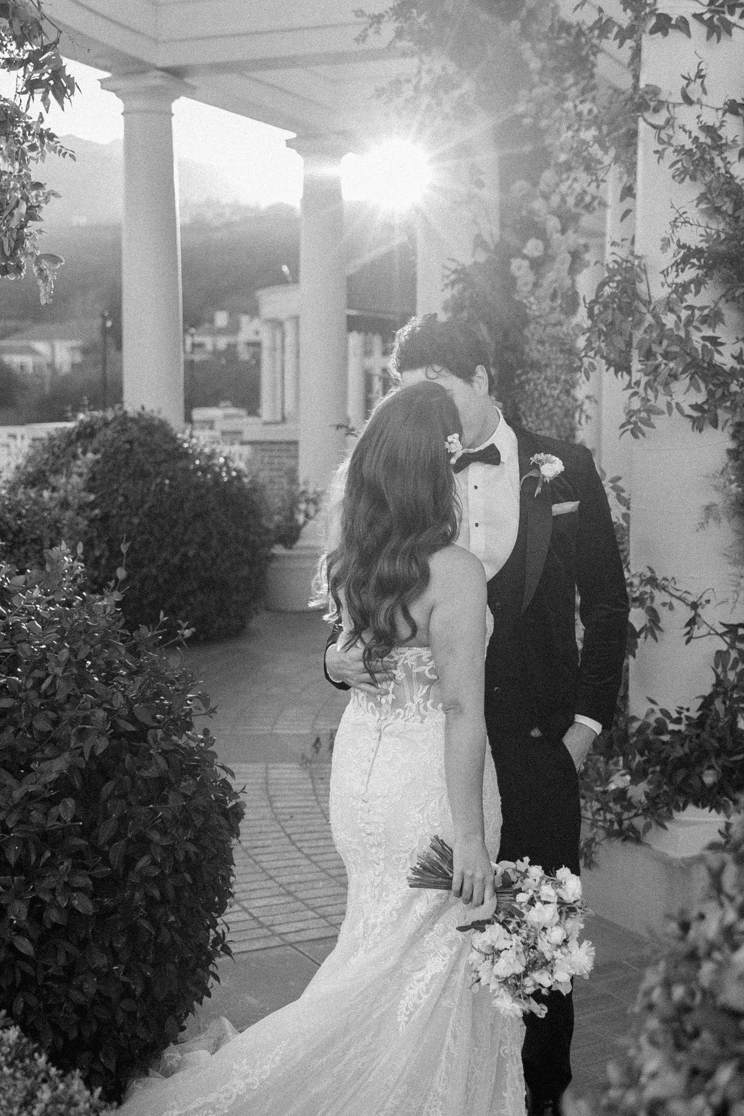 Black and white wedding photos show a romantic couple in formal attire posing together on a porch with white columns.