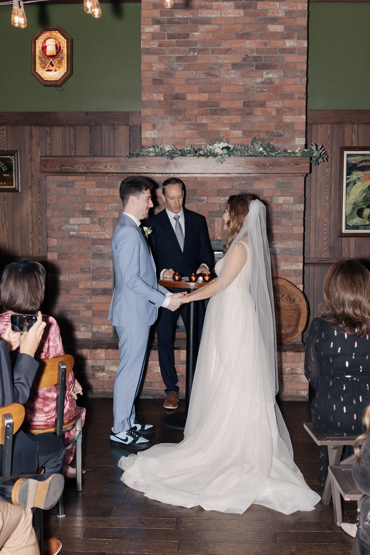A wedding ceremony in progress inside a rustic venue with exposed brick walls and wooden floors.