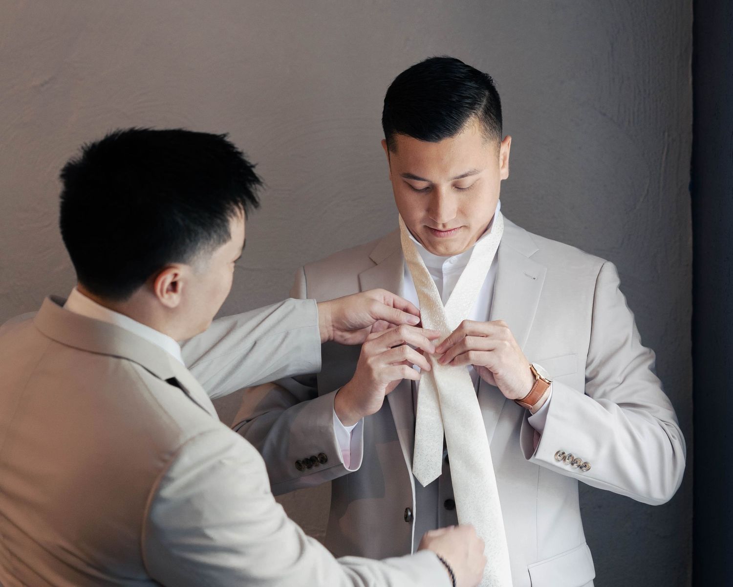 Close-up sequence of a person adjusting a white tie and collar in formal attire.