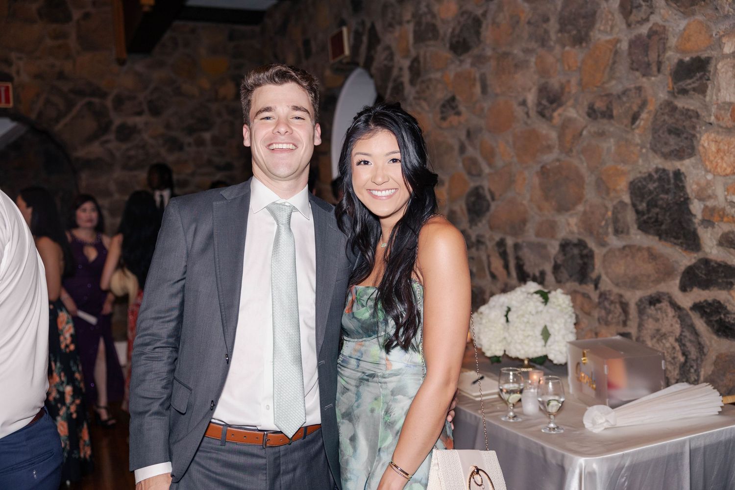 Wedding guests socializing in a rustic stone-walled event space.