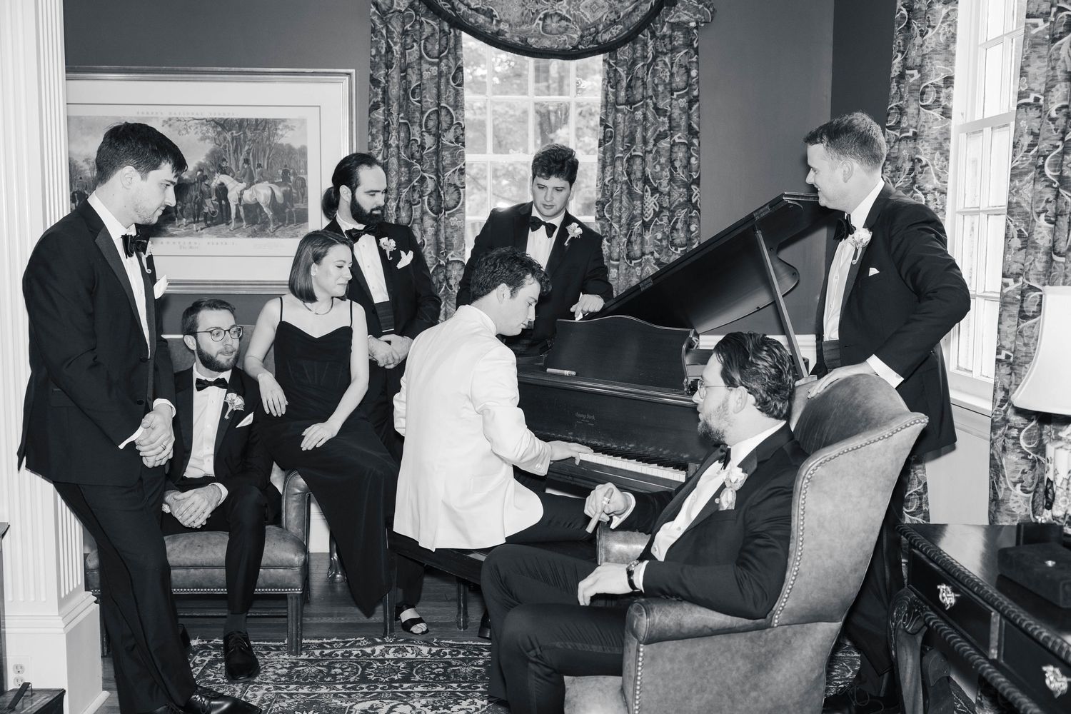 A vintage black and white photograph shows couples dancing at a formal social gathering in an ornate room.