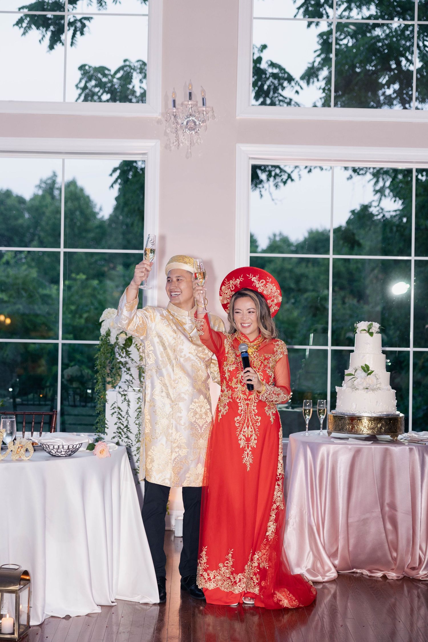 Traditional Vietnamese wedding celebration with couple in red and gold attire dancing together at elegant reception venue.
