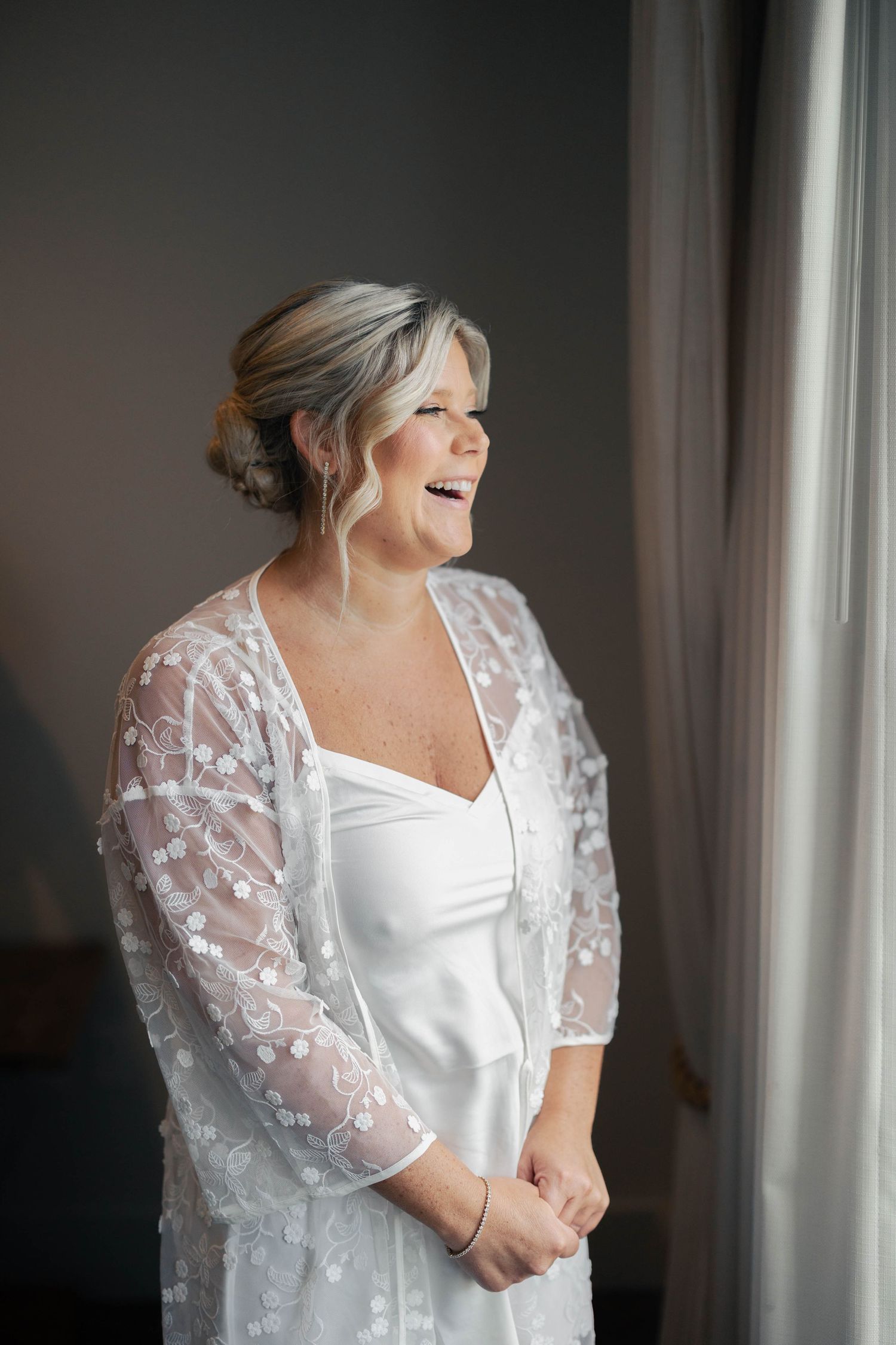 Elegant white wedding dress with sheer lace sleeves photographed in soft natural light.
