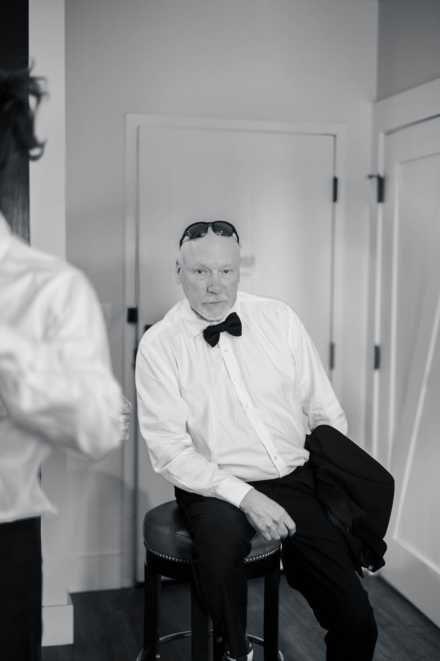Person in white dress shirt and bow tie sitting in contemplative pose.