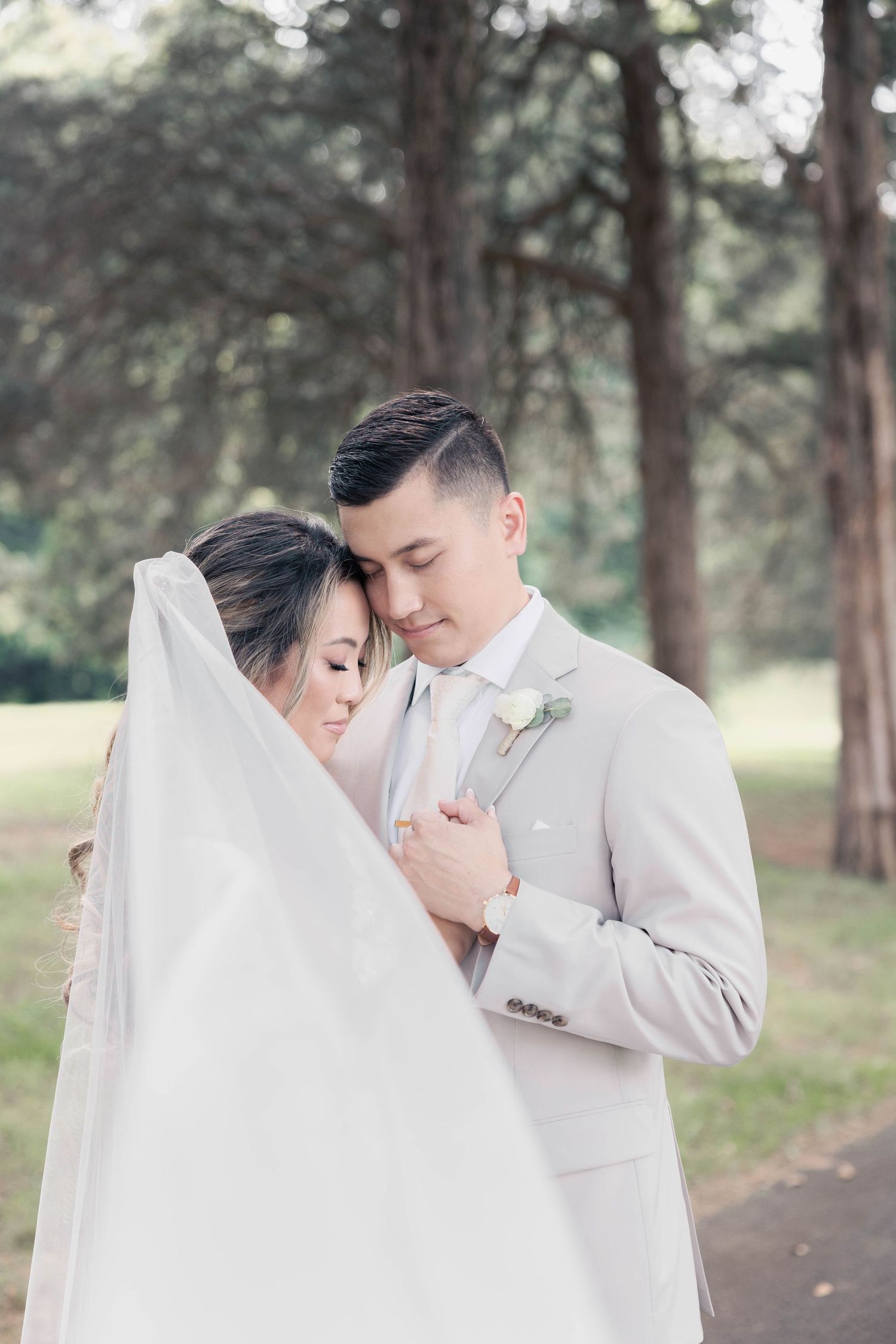 Tender romantic moment between newlyweds among tall pine trees.