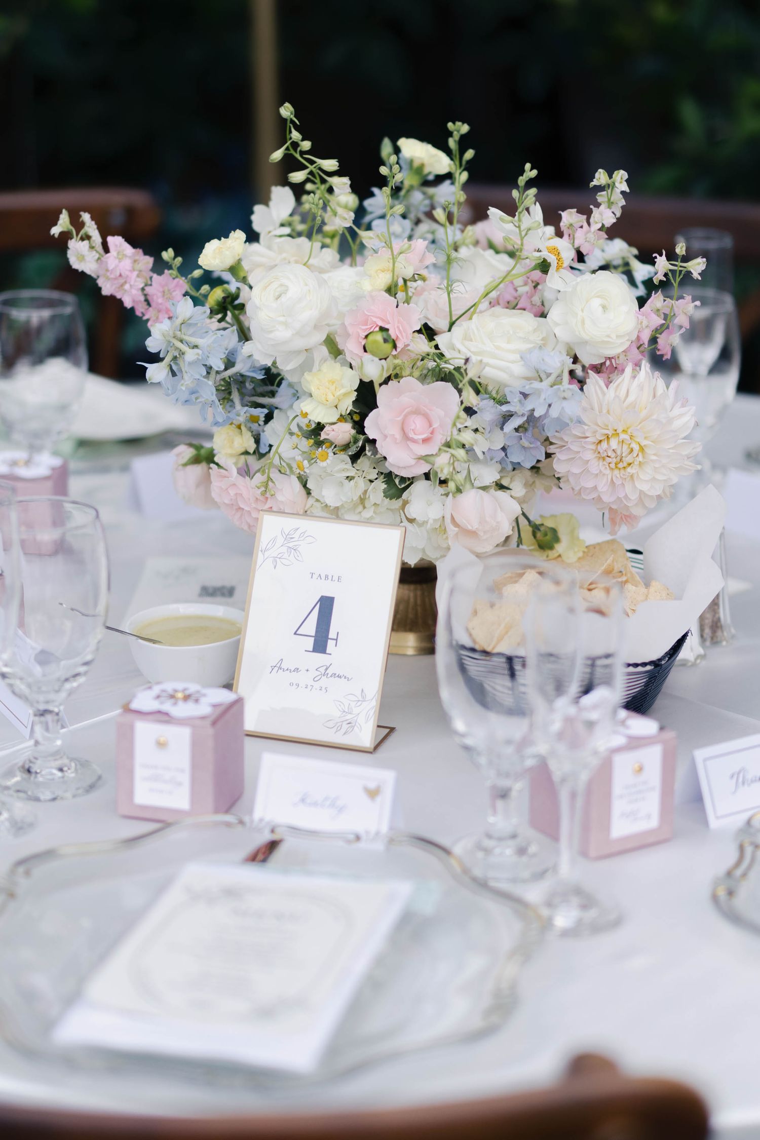 Elegant wedding reception table settings with blush pink and white floral centerpieces and numbered table cards.