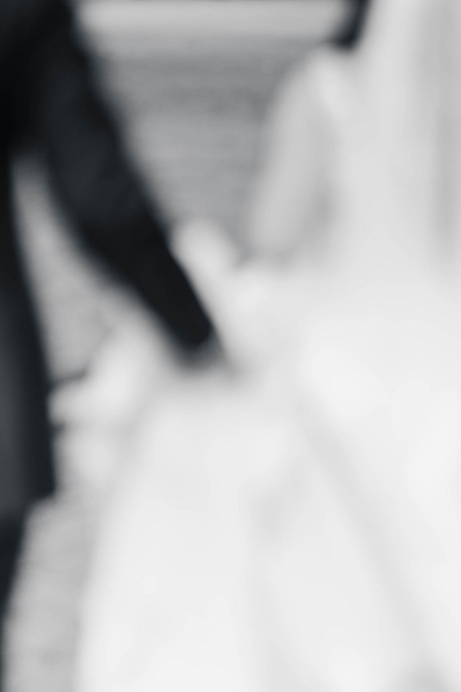 A series of abstract black and white shapes creating a gradient pattern with varying levels of contrast and blur.