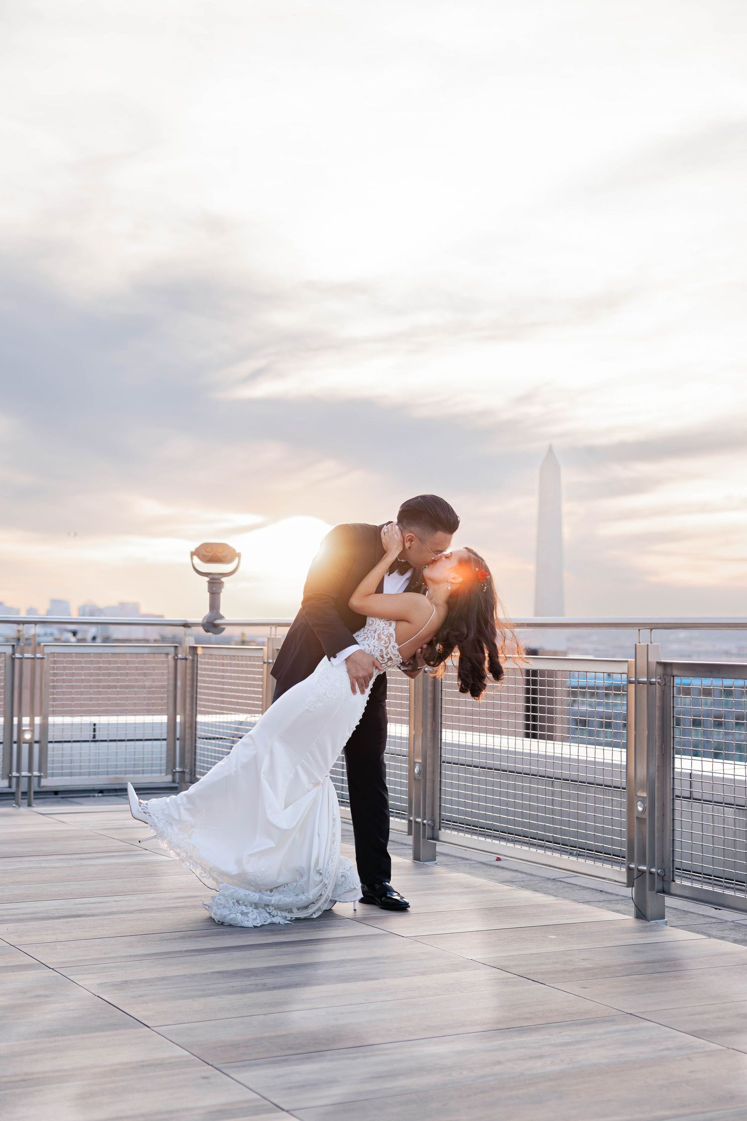 A romantic dance dip pose sequence on a rooftop terrace at sunset with city views in the background.
