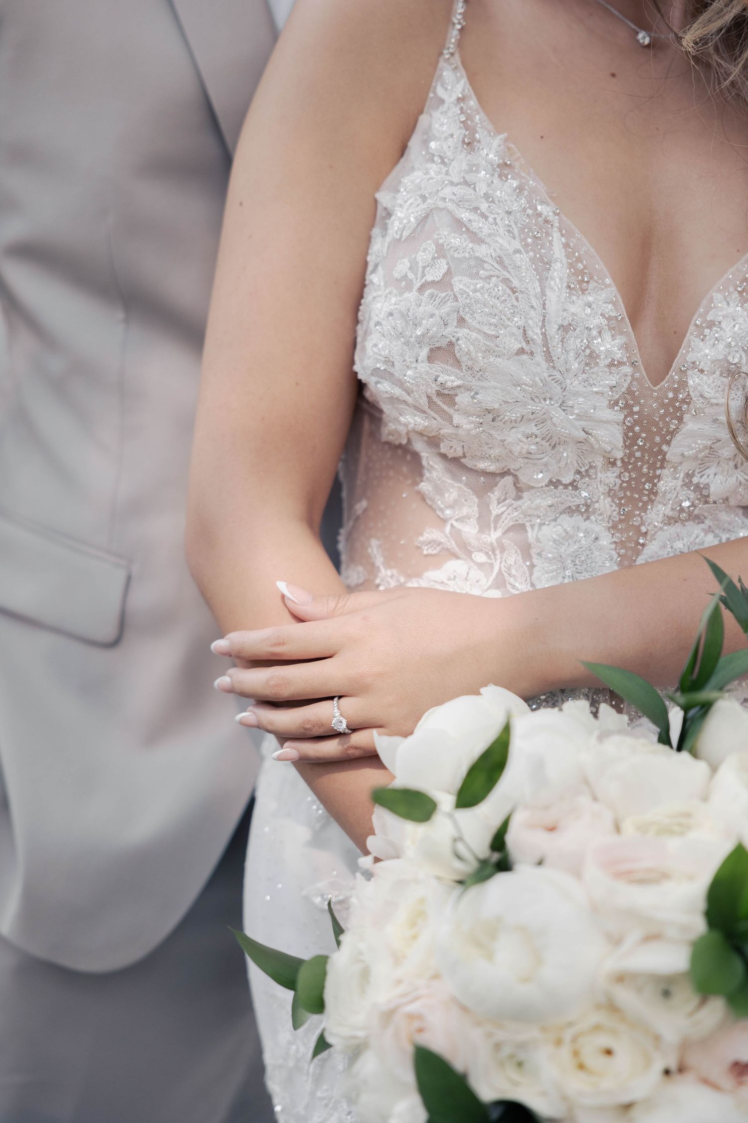 Detailed shots of an intricate lace wedding dress bodice with white floral bouquet.